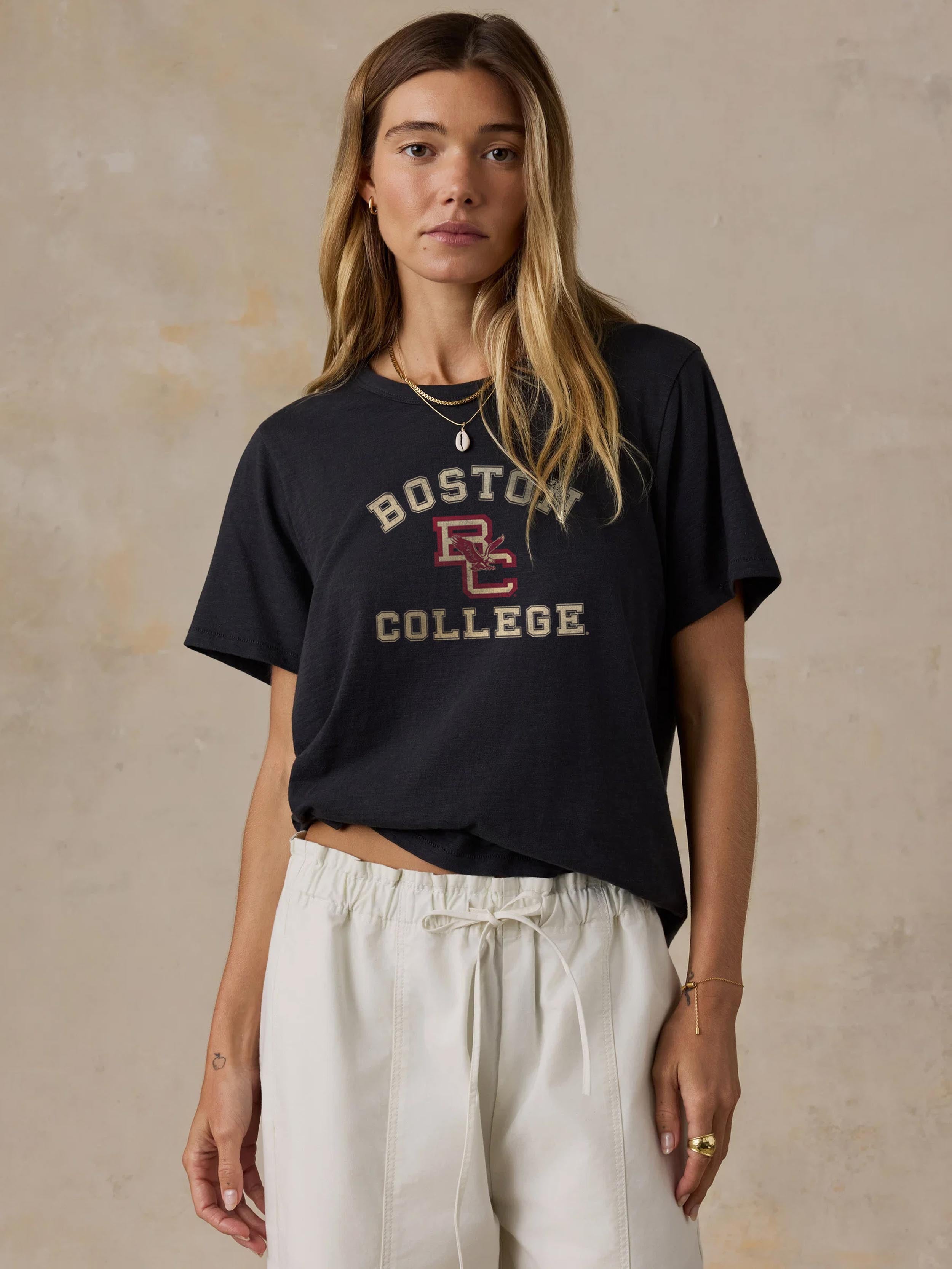A woman wearing a black Boston College tee and white pants