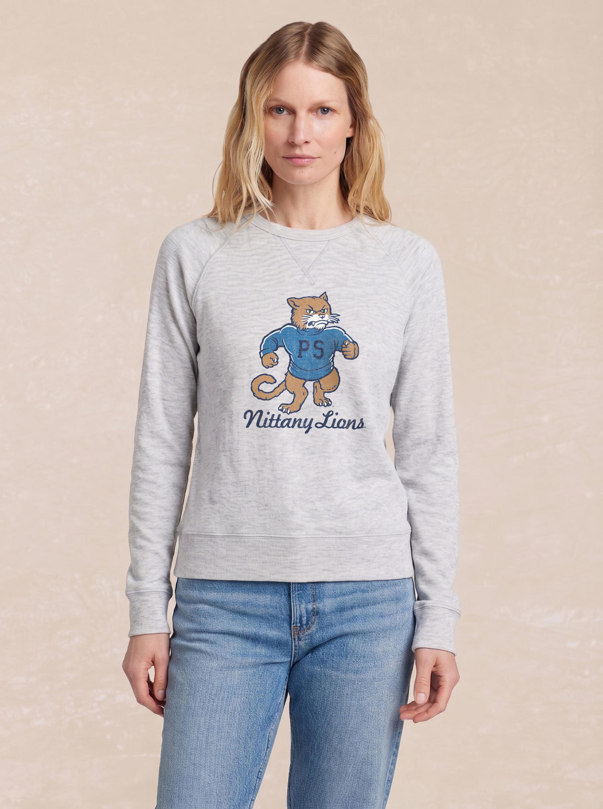 A woman wearing a grey Penn State graphic crewneck and blue jeans, image 1 of 1