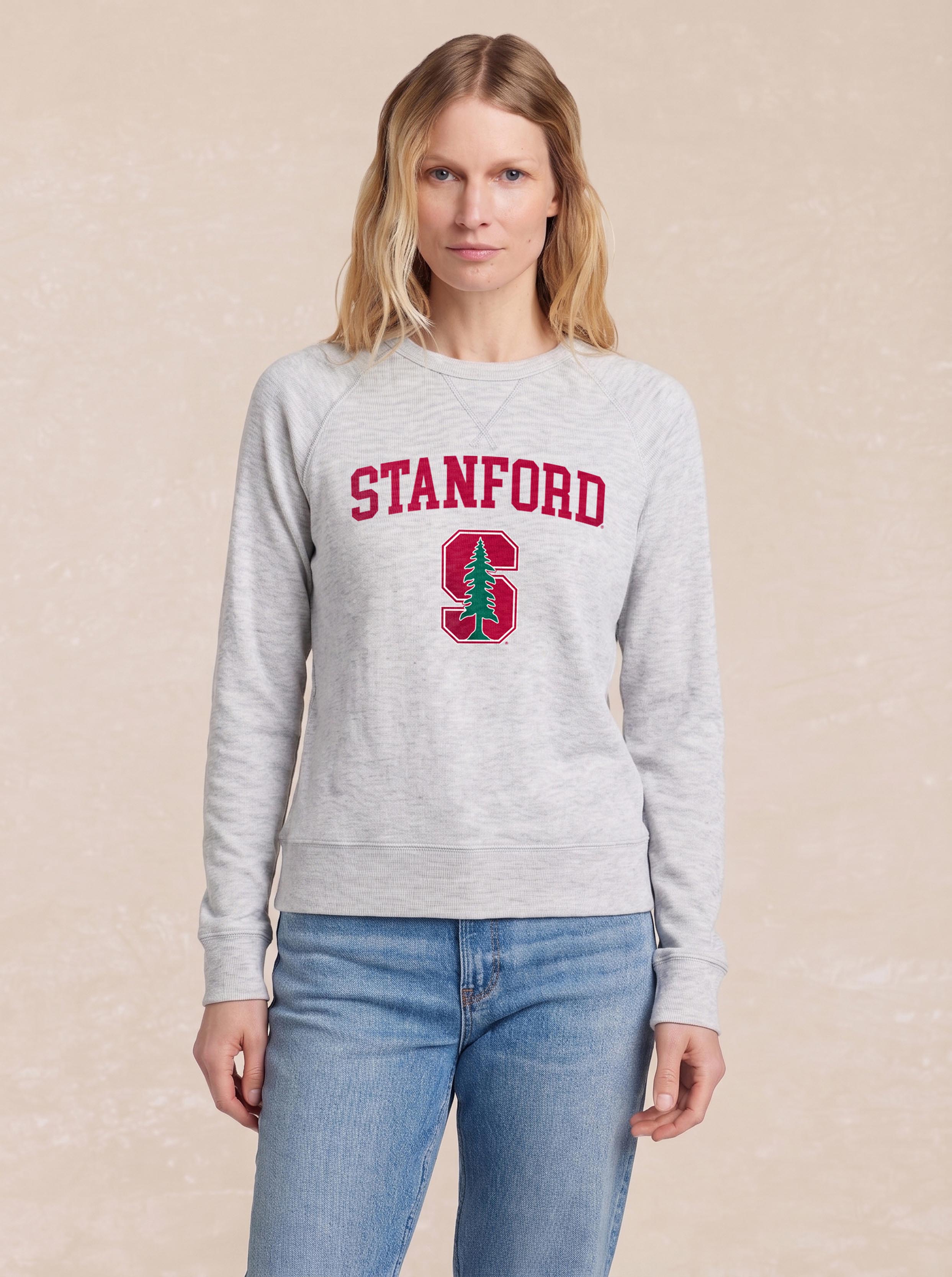 A woman wearing a grey Stanford crewneck and blue jeans