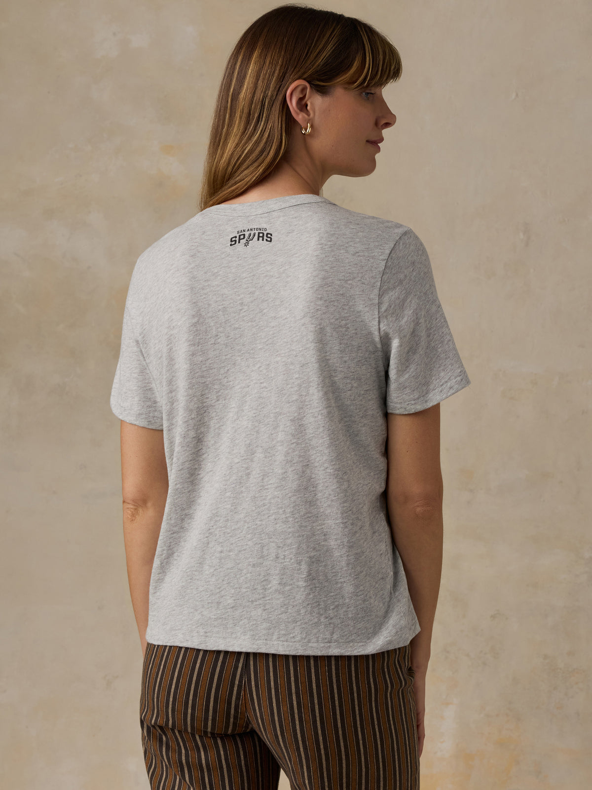 A woman viewed from behind wearing a grey San Antonio Spurs tee, image 2 of 4