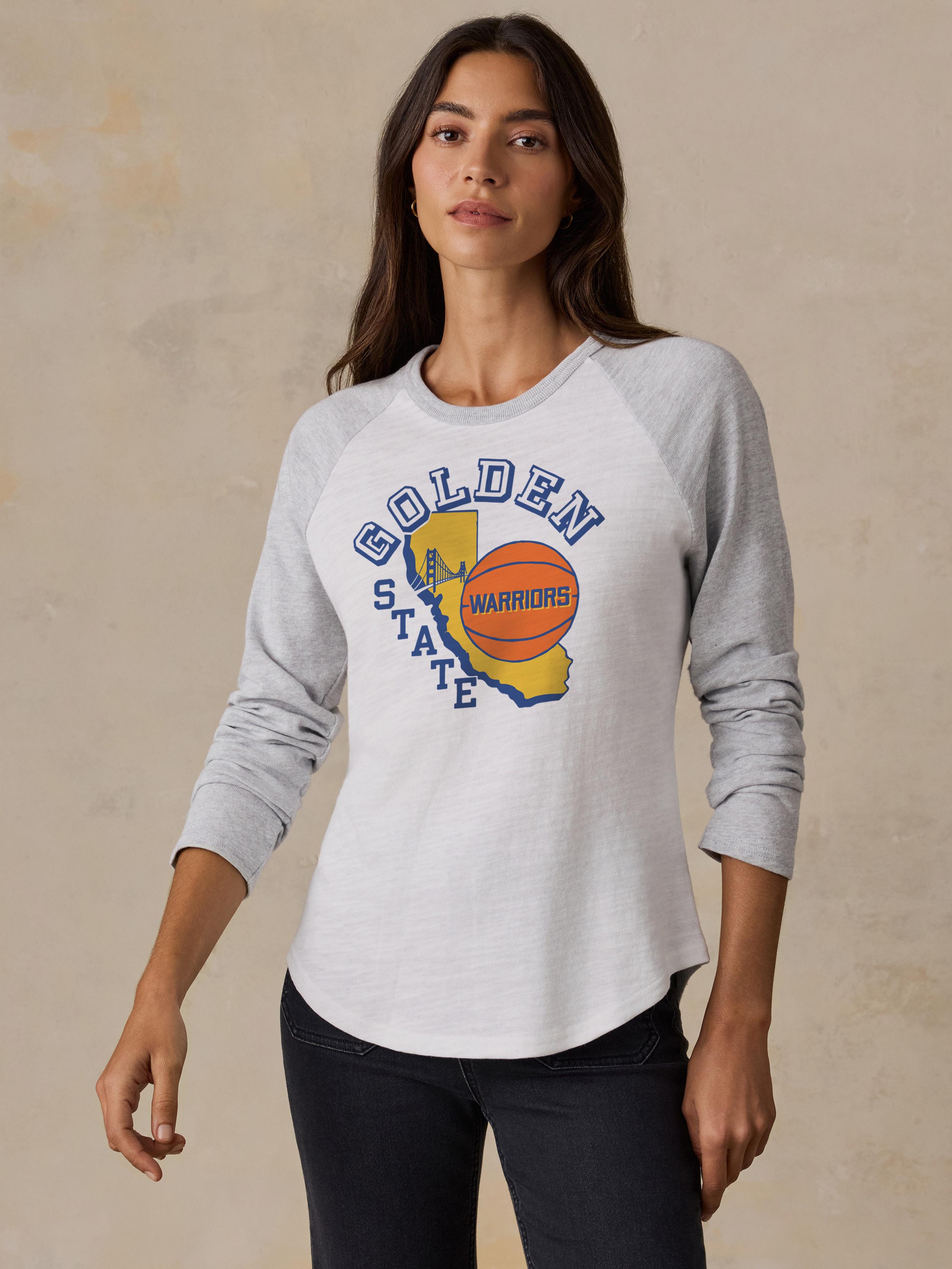 A woman wearing a white and grey Golden State Warriors baseball tee