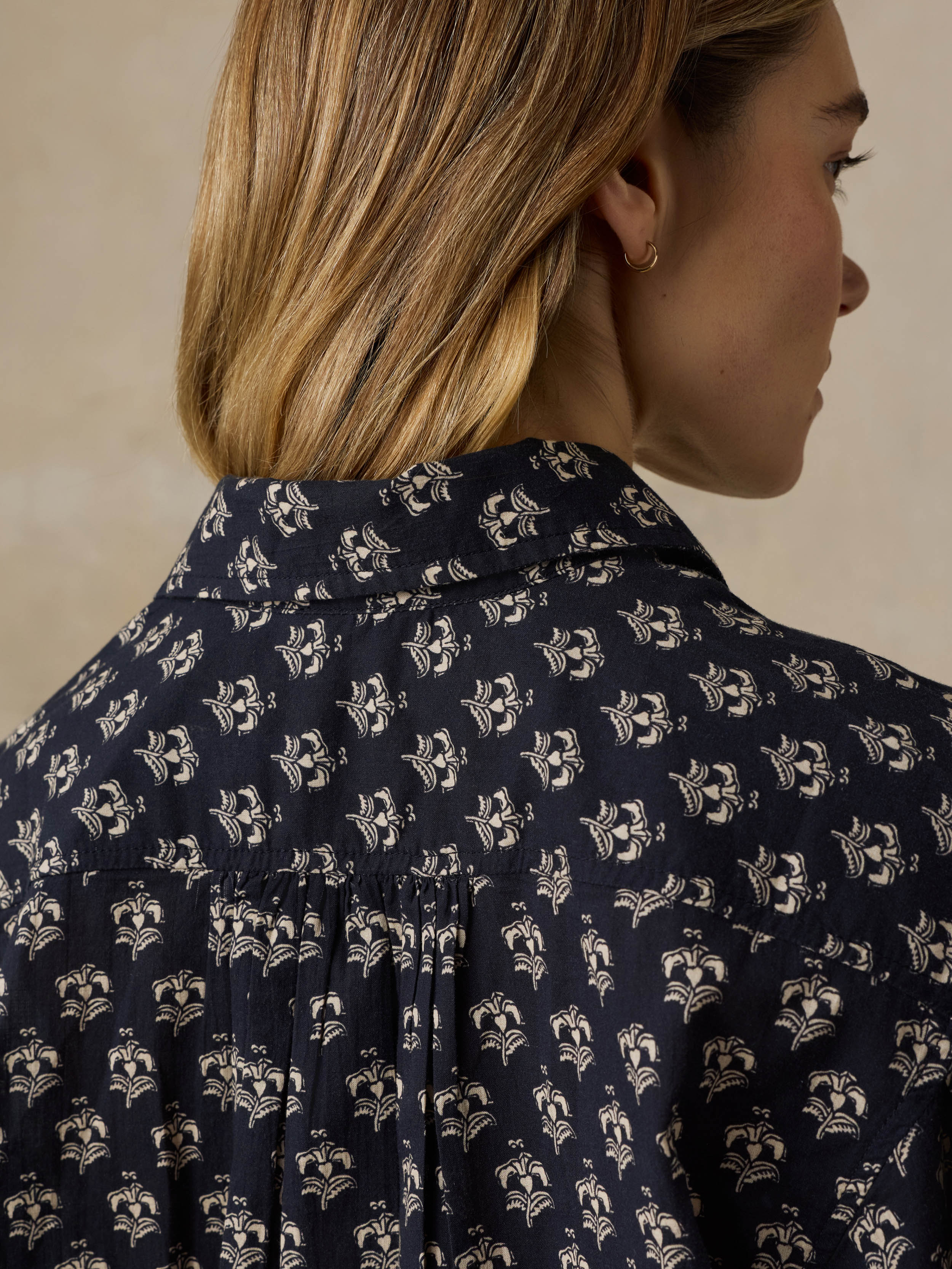 Woman wearing a dark patterned blouse against a beige background