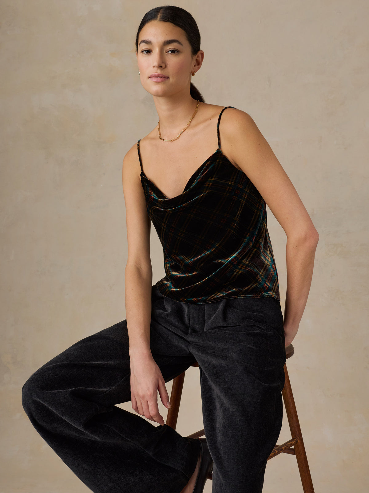 A woman wearing a plaid velvet top and black pants, image 4 of 5