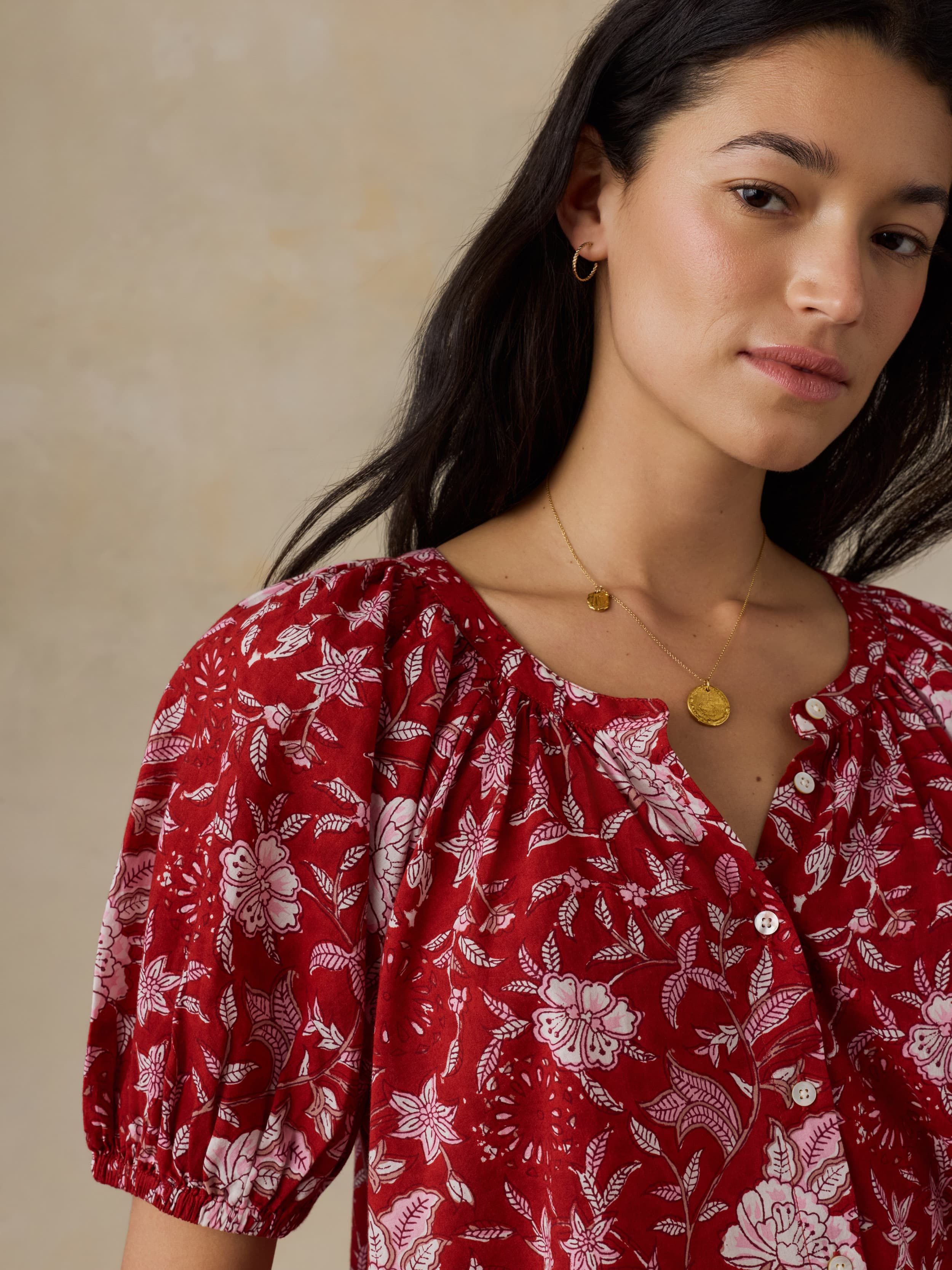 Woman wearing a red floral blouse against a beige background