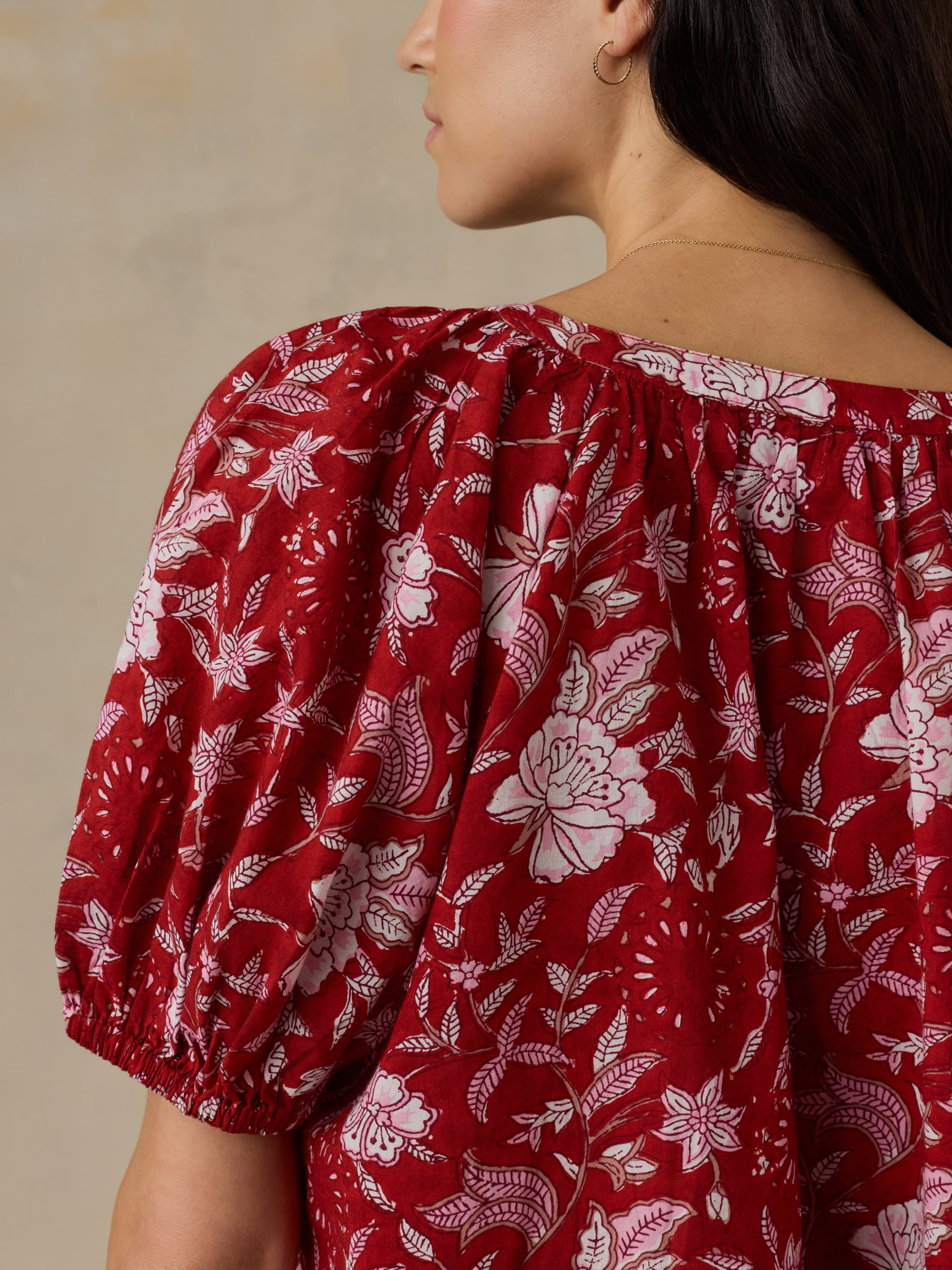Woman wearing a red floral blouse against a beige background