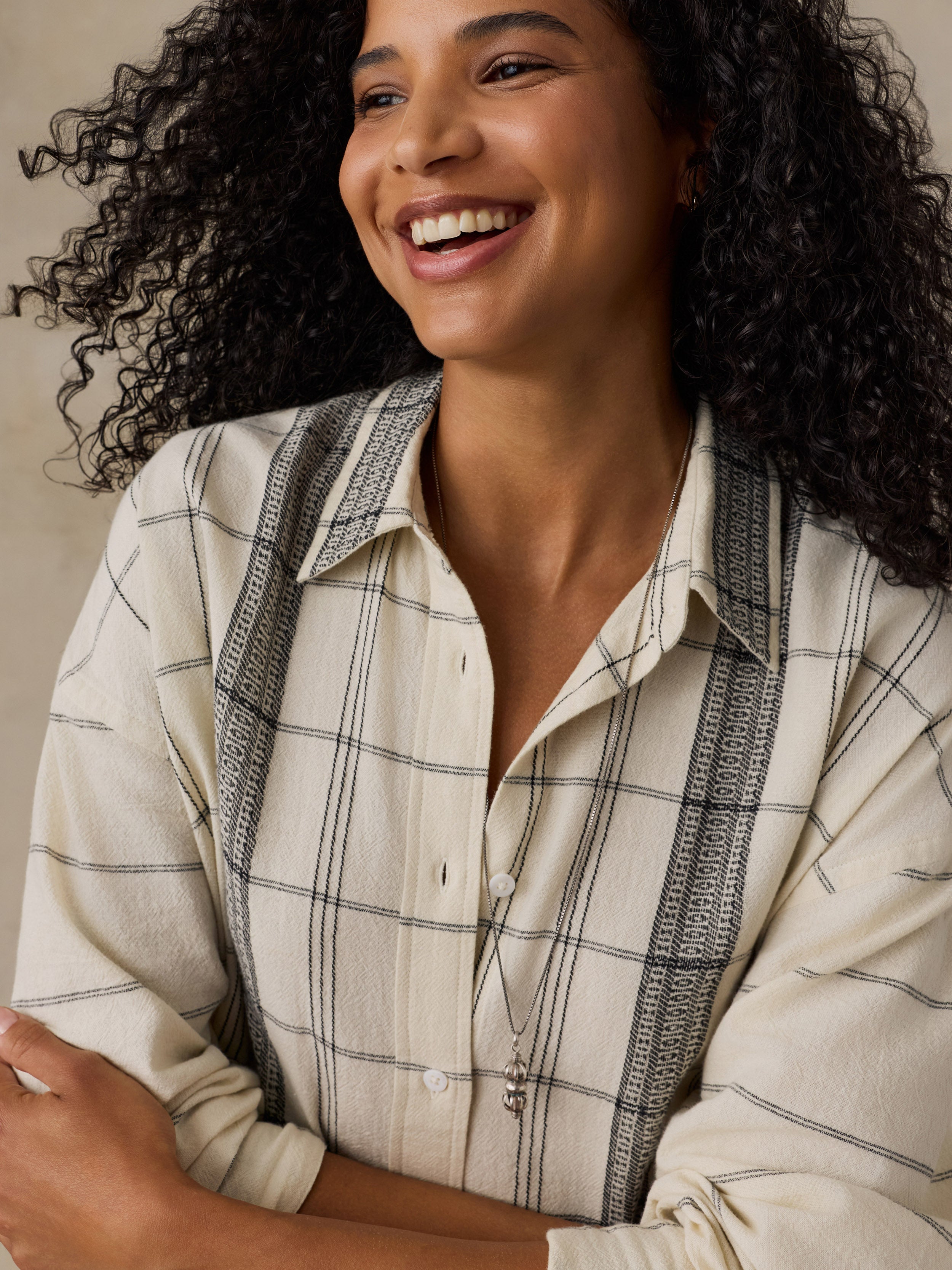 Woman wearing a white and black plaid shirt against a beige background