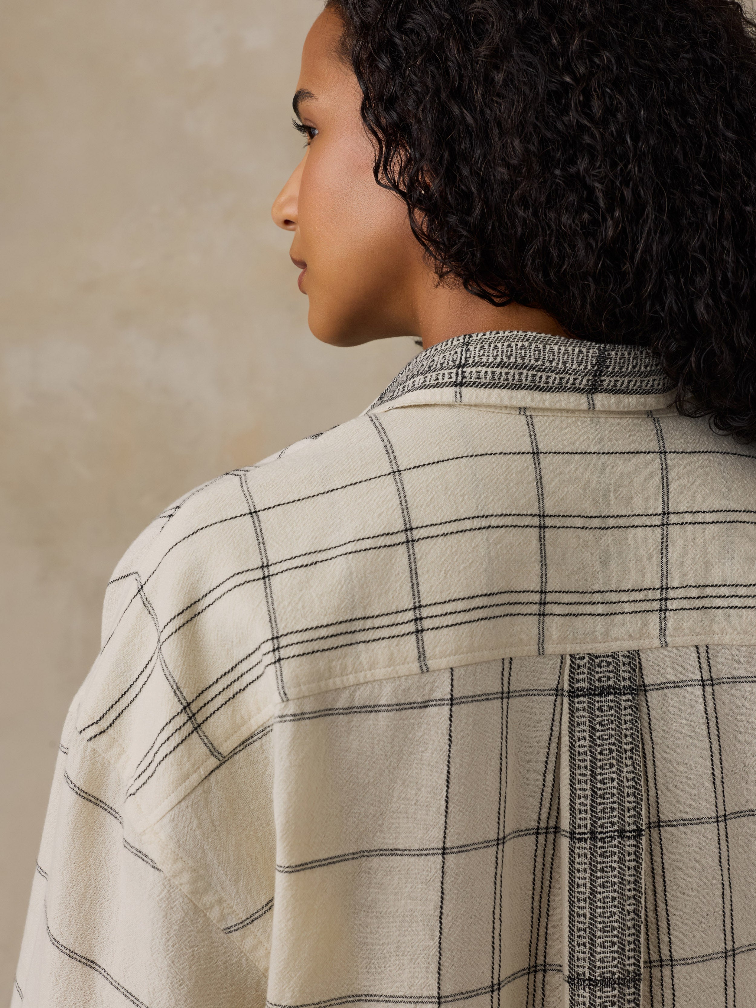 Woman wearing a white and black plaid shirt against a beige background