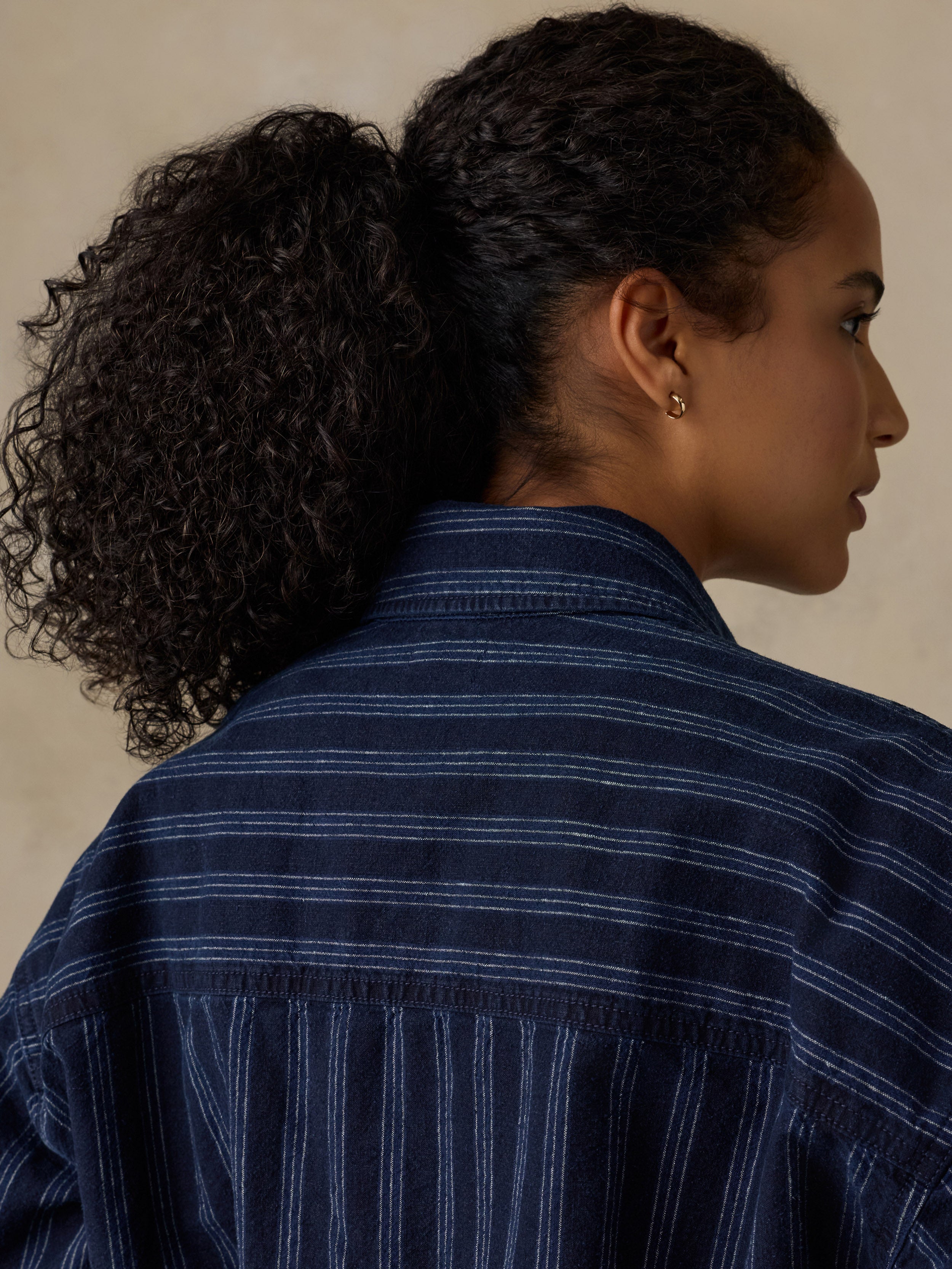 Woman wearing a navy striped overshirt against a beige background