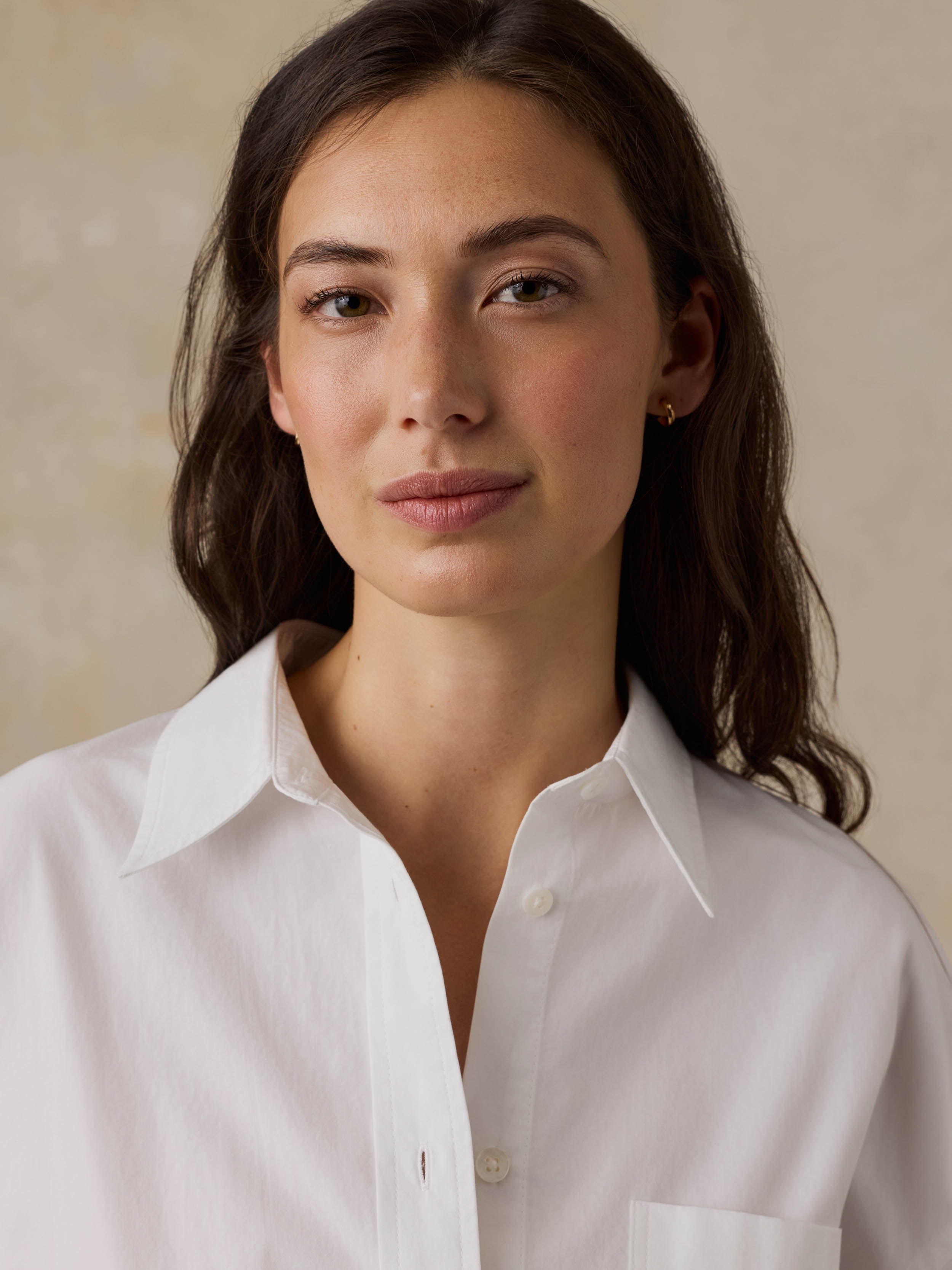 Woman wearing a white shirt against a beige background
