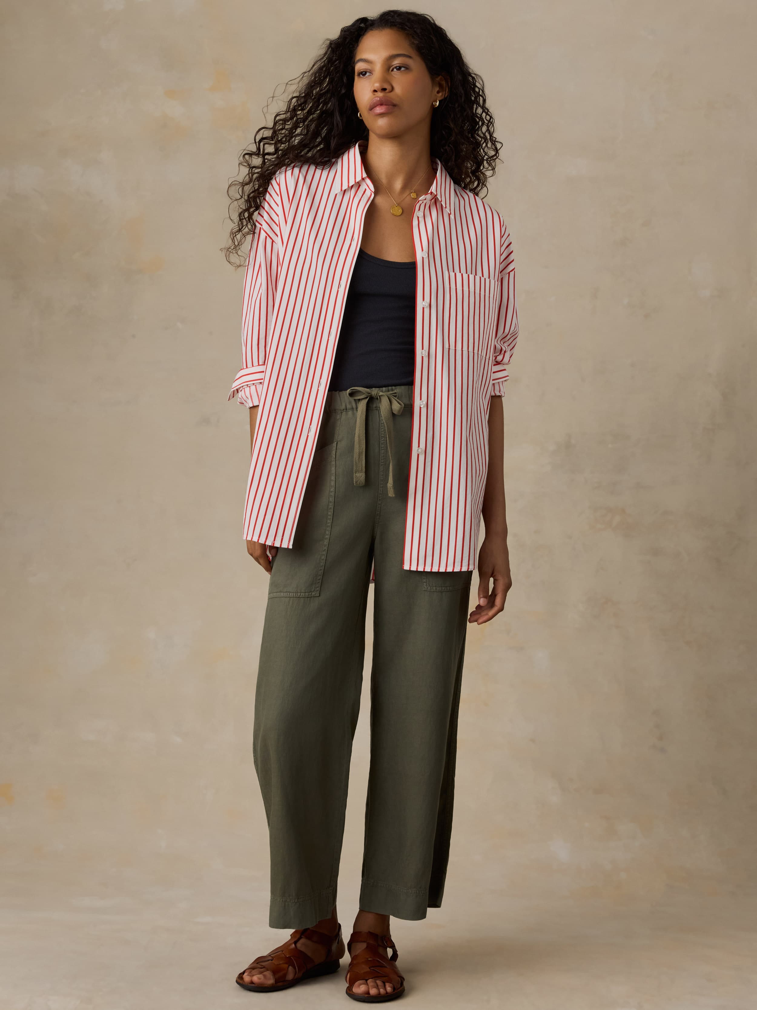 Woman wearing a red and white striped shirt and green pants against a beige background