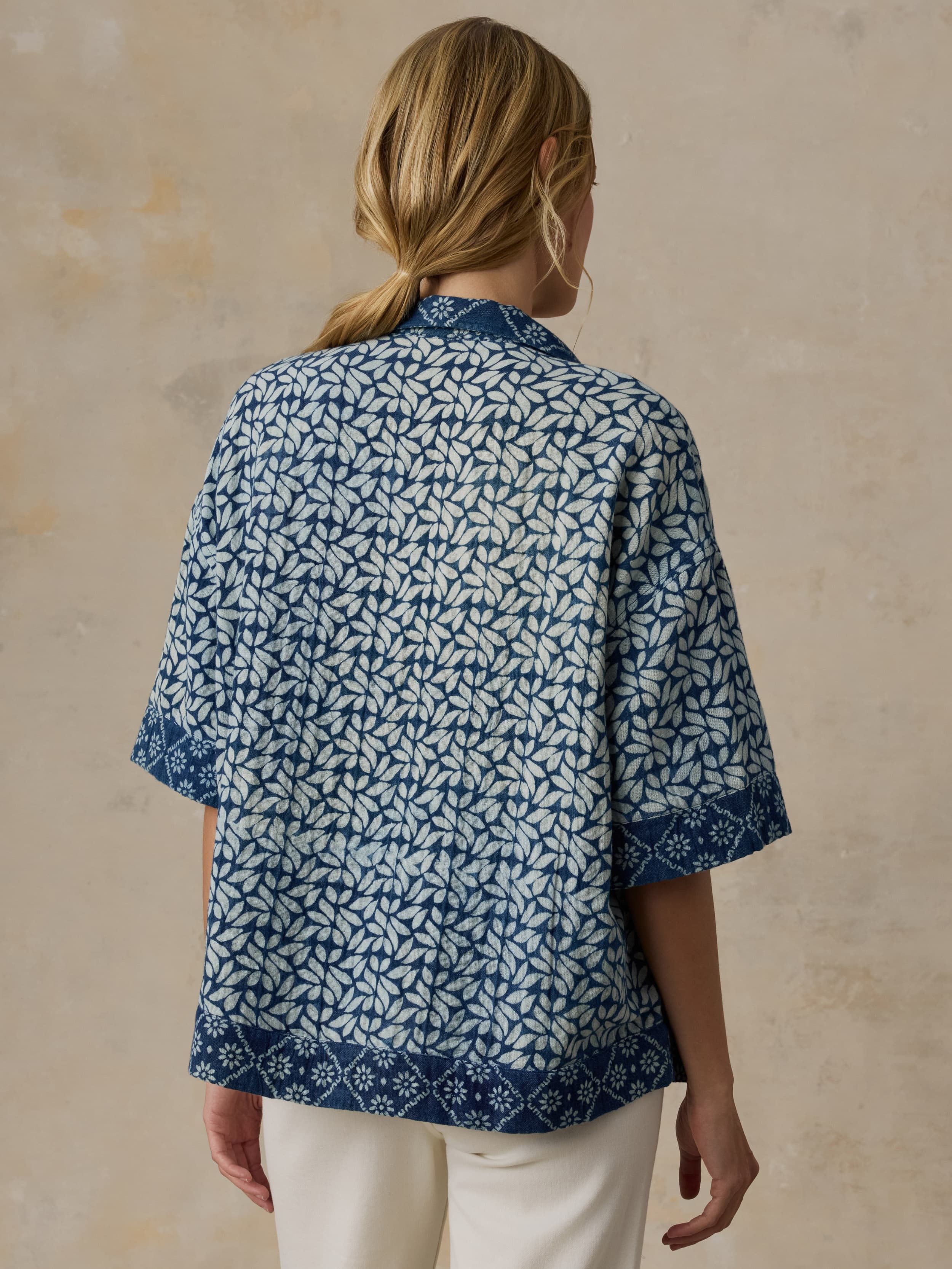 Woman wearing a blue patterned shirt against a beige background