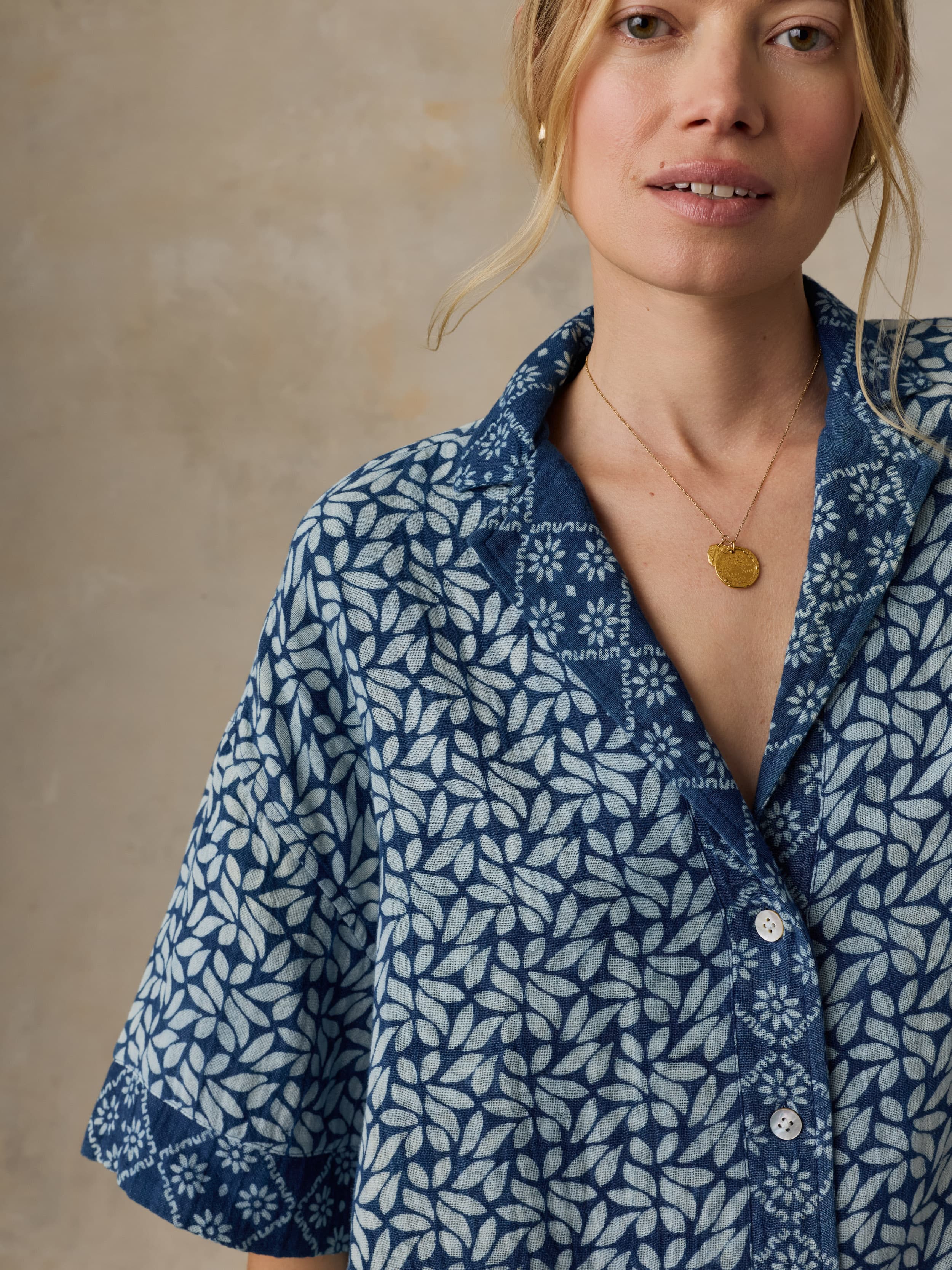 Woman wearing a blue patterned shirt against a beige background