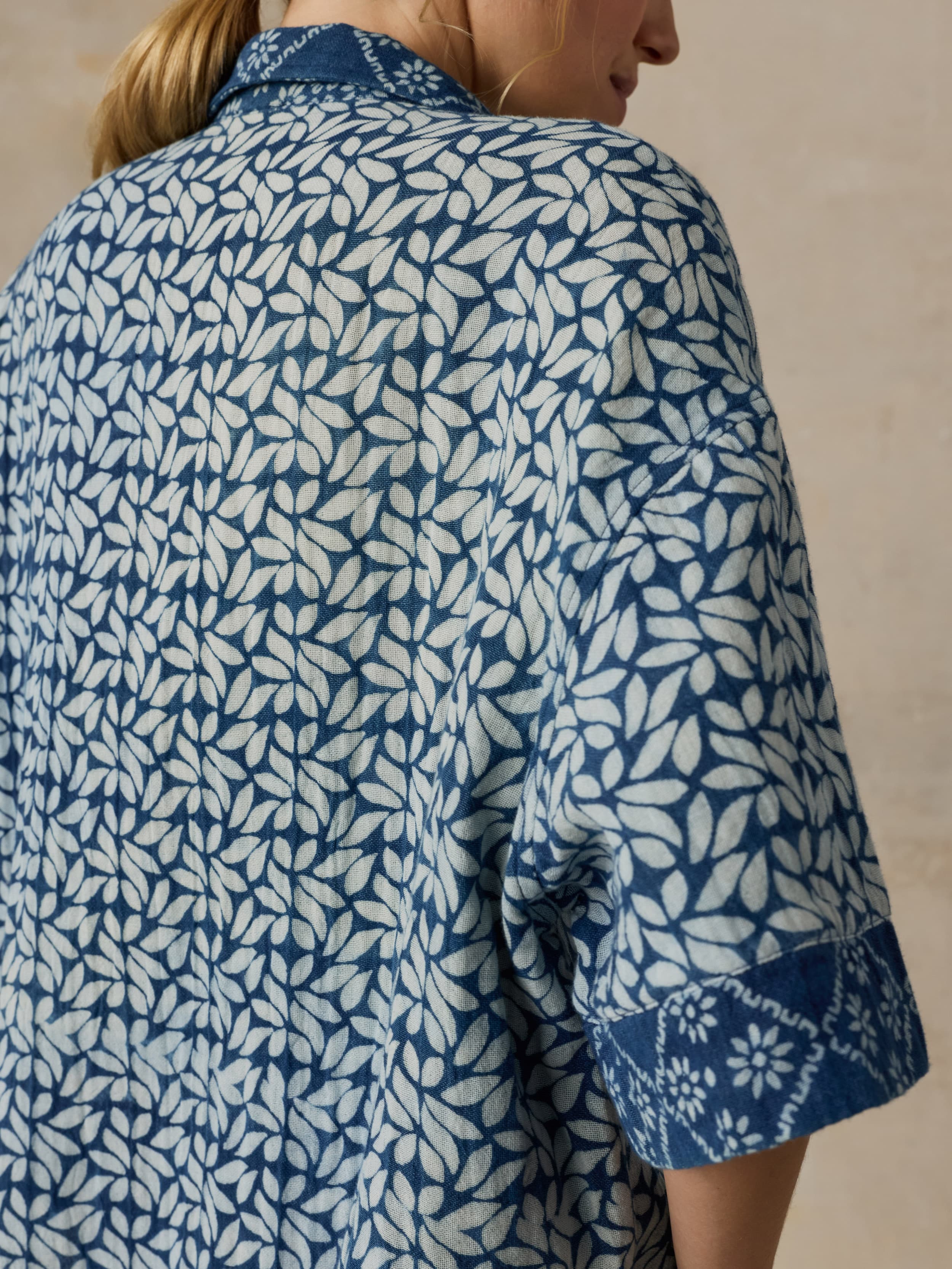 Woman wearing a blue patterned shirt against a beige background