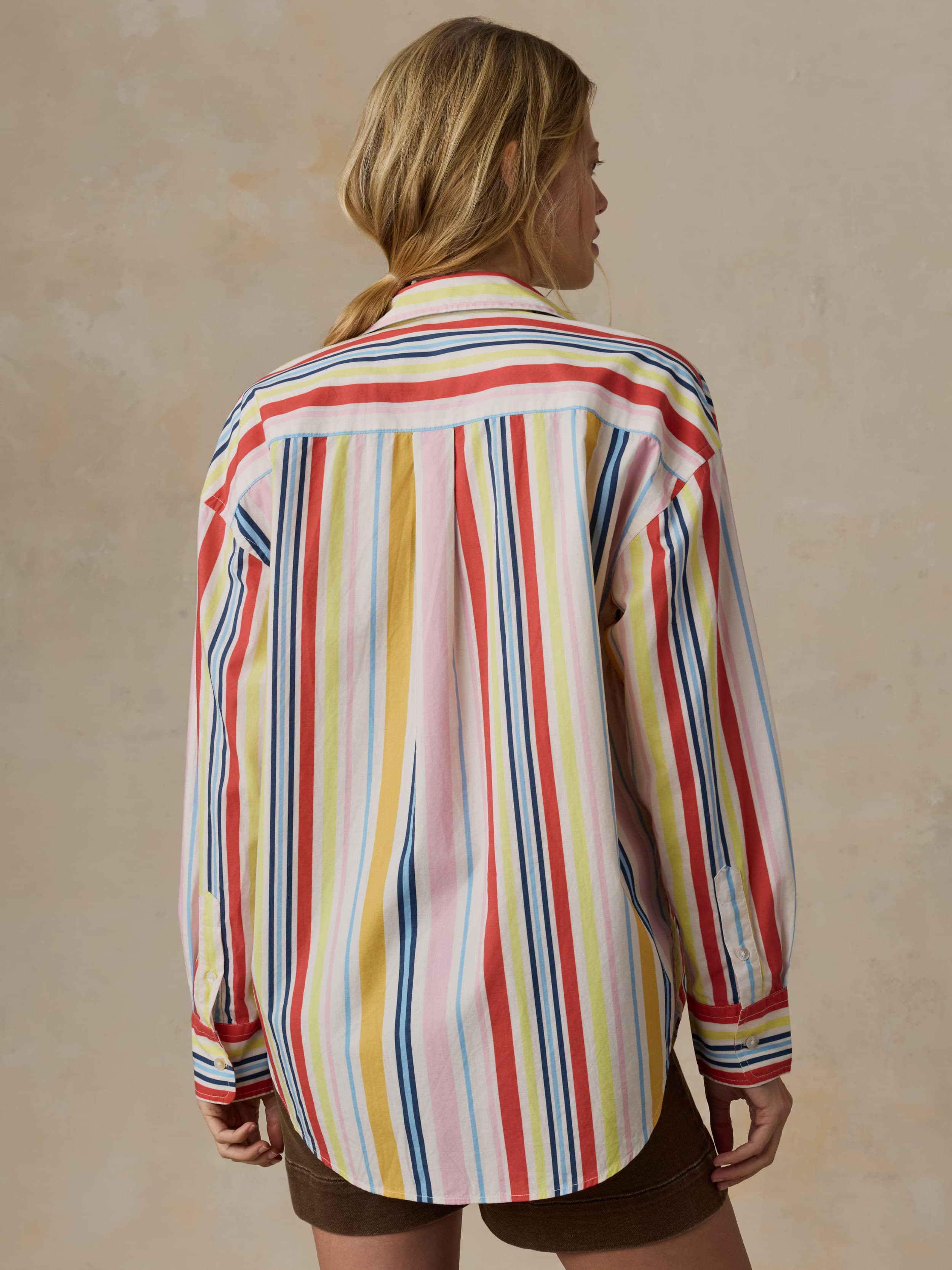 Woman wearing a colorful striped shirt against a beige background