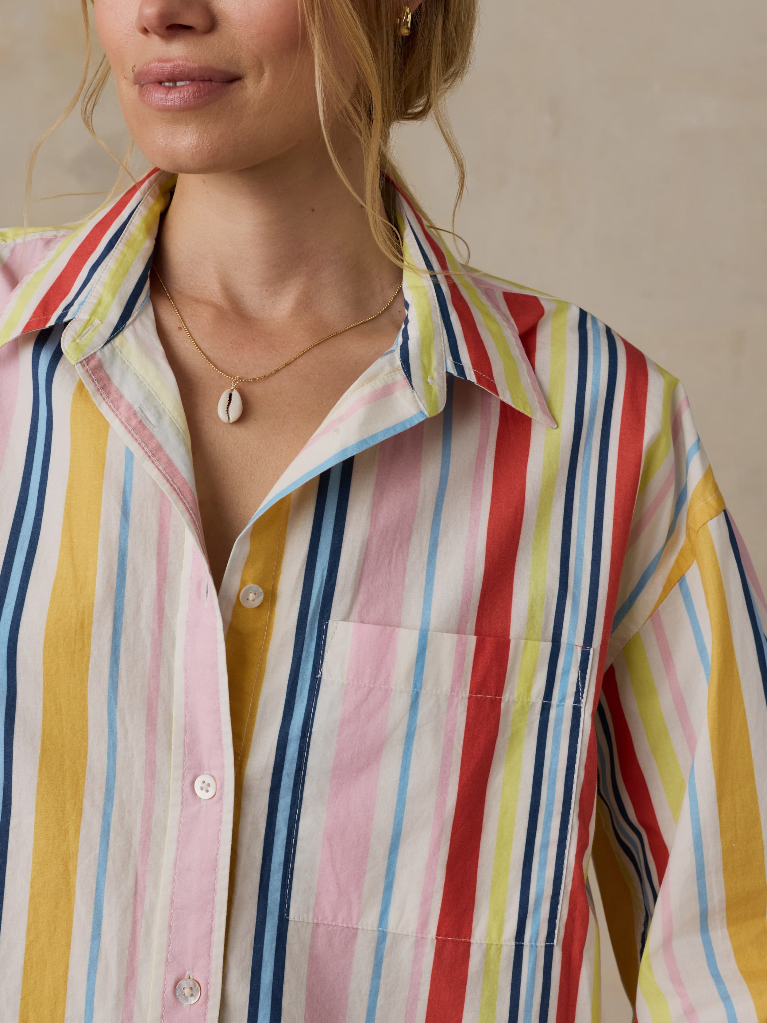 Close-up of a person wearing a colorful striped shirt with a neutral background