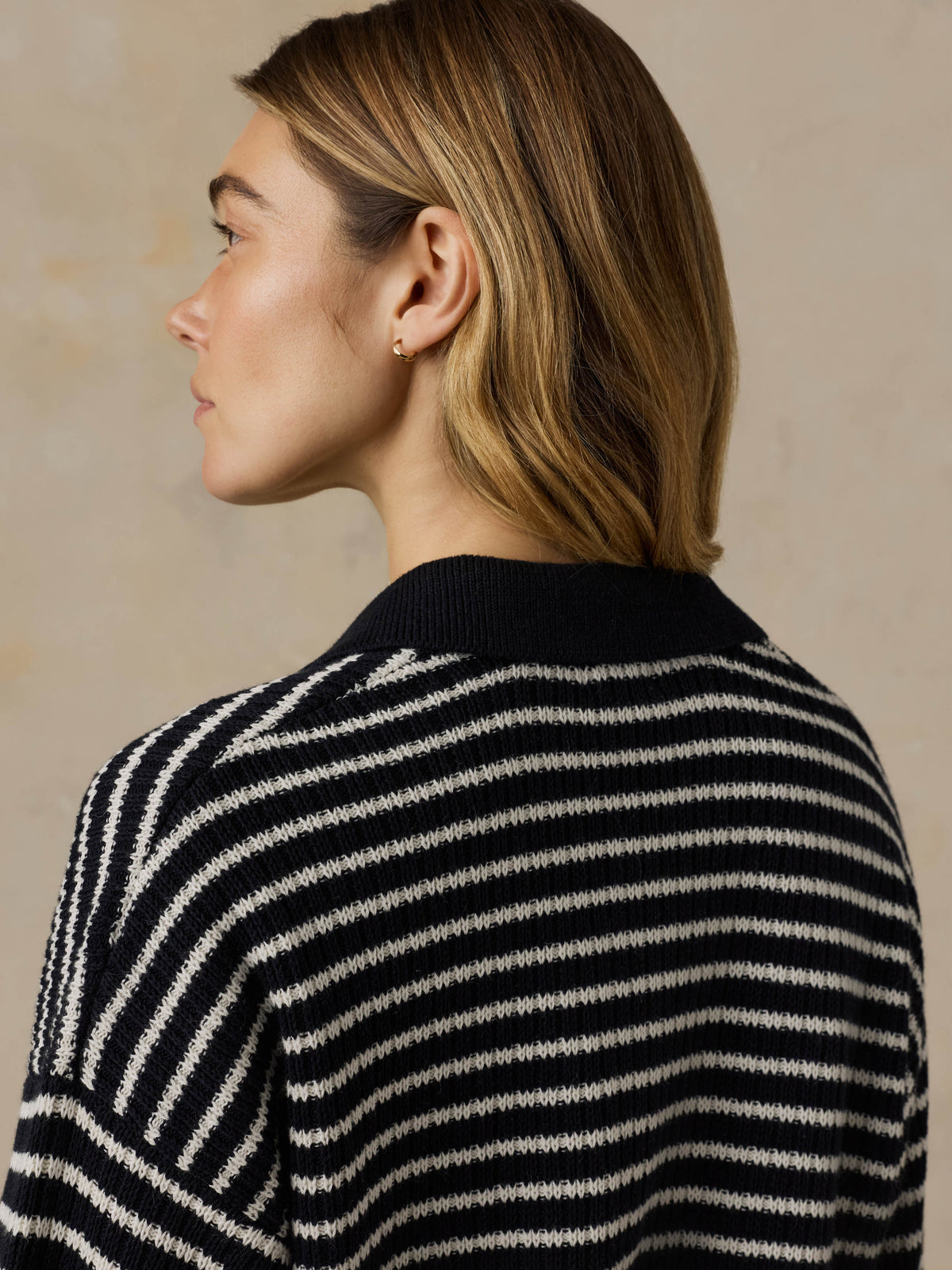 Woman wearing a blue and white striped sweater against a beige background, image 4 of 5