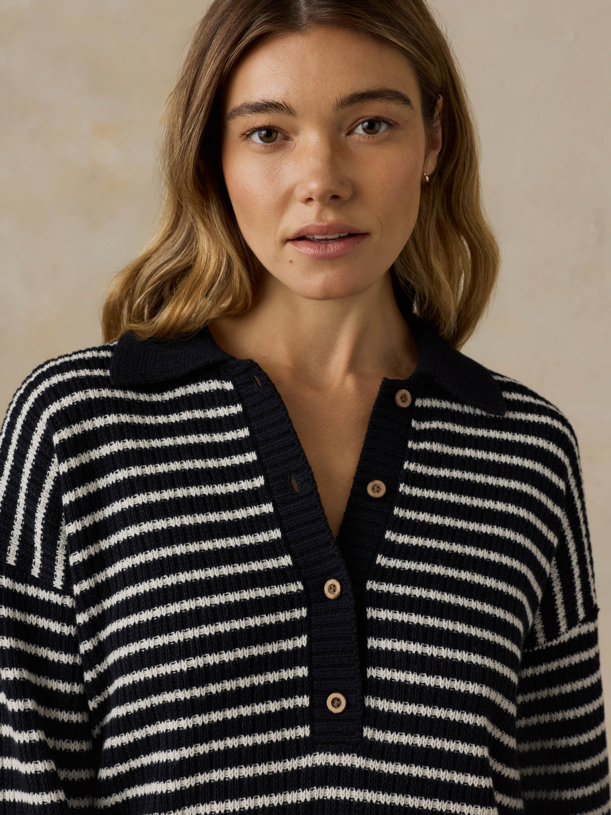Woman wearing a blue and white striped sweater against a beige background, image 2 of 5