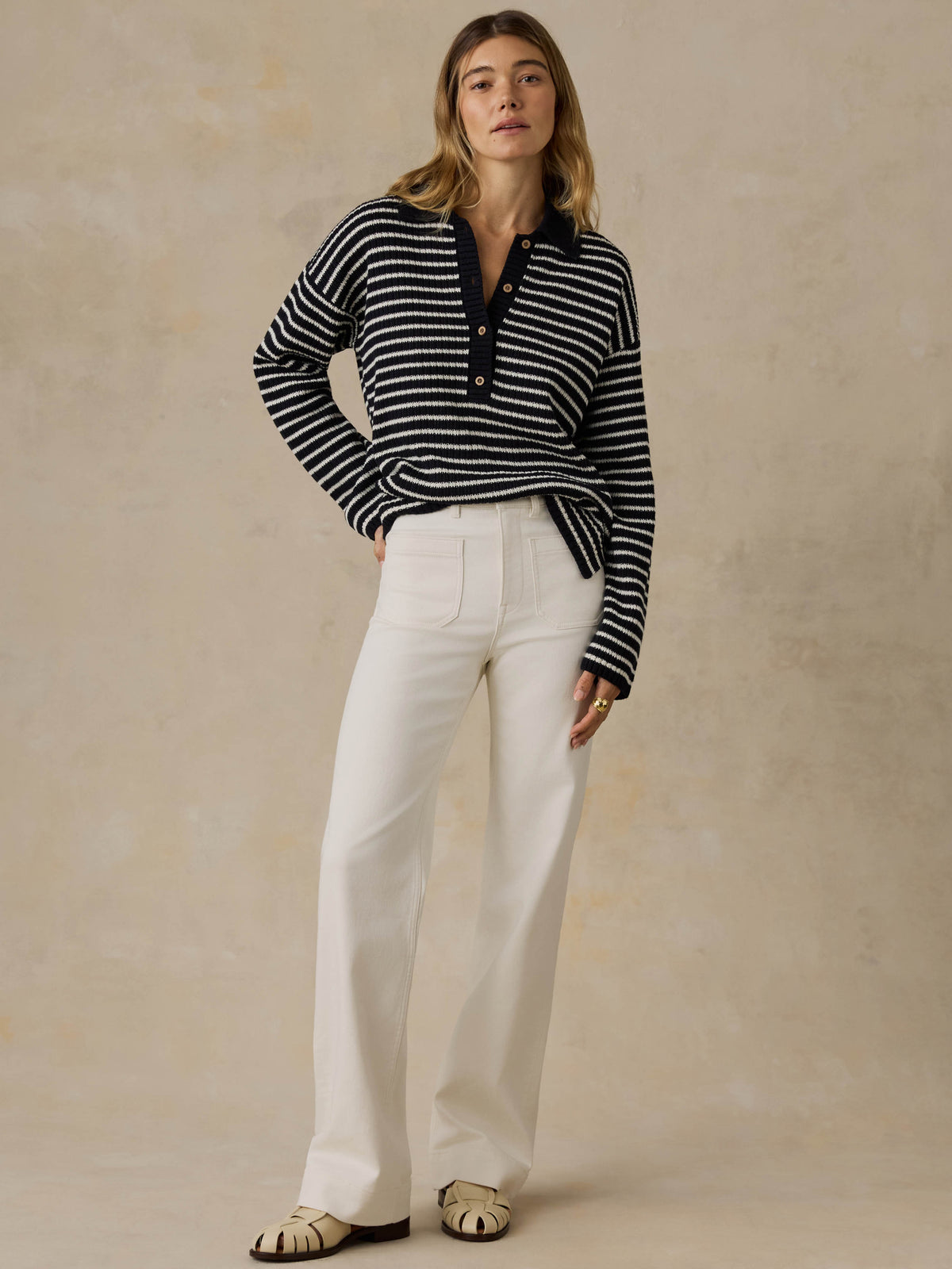 Woman wearing a blue and white striped sweater and white pants against a beige background, image 5 of 5