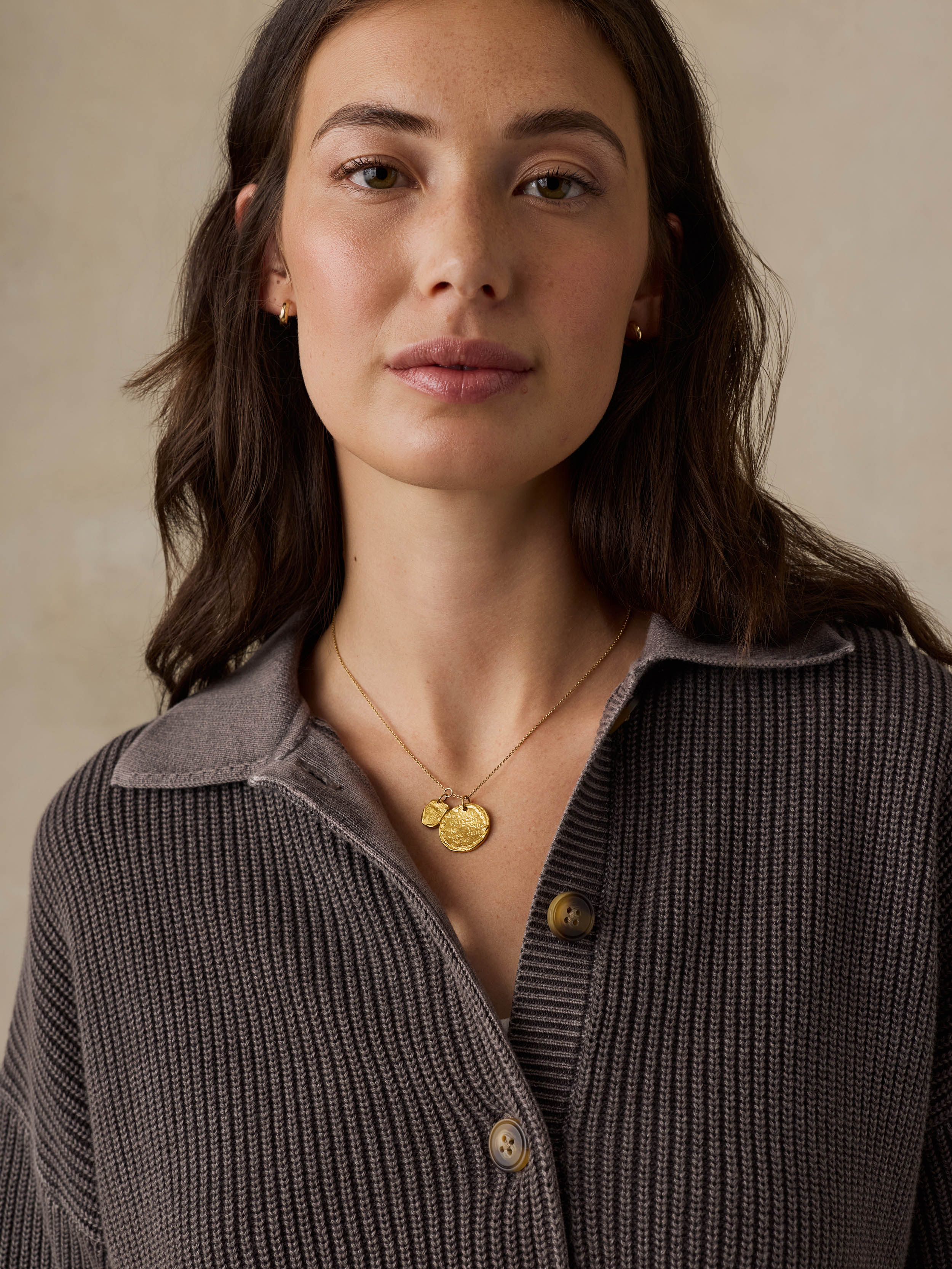 Woman wearing a brown sweater against a beige background