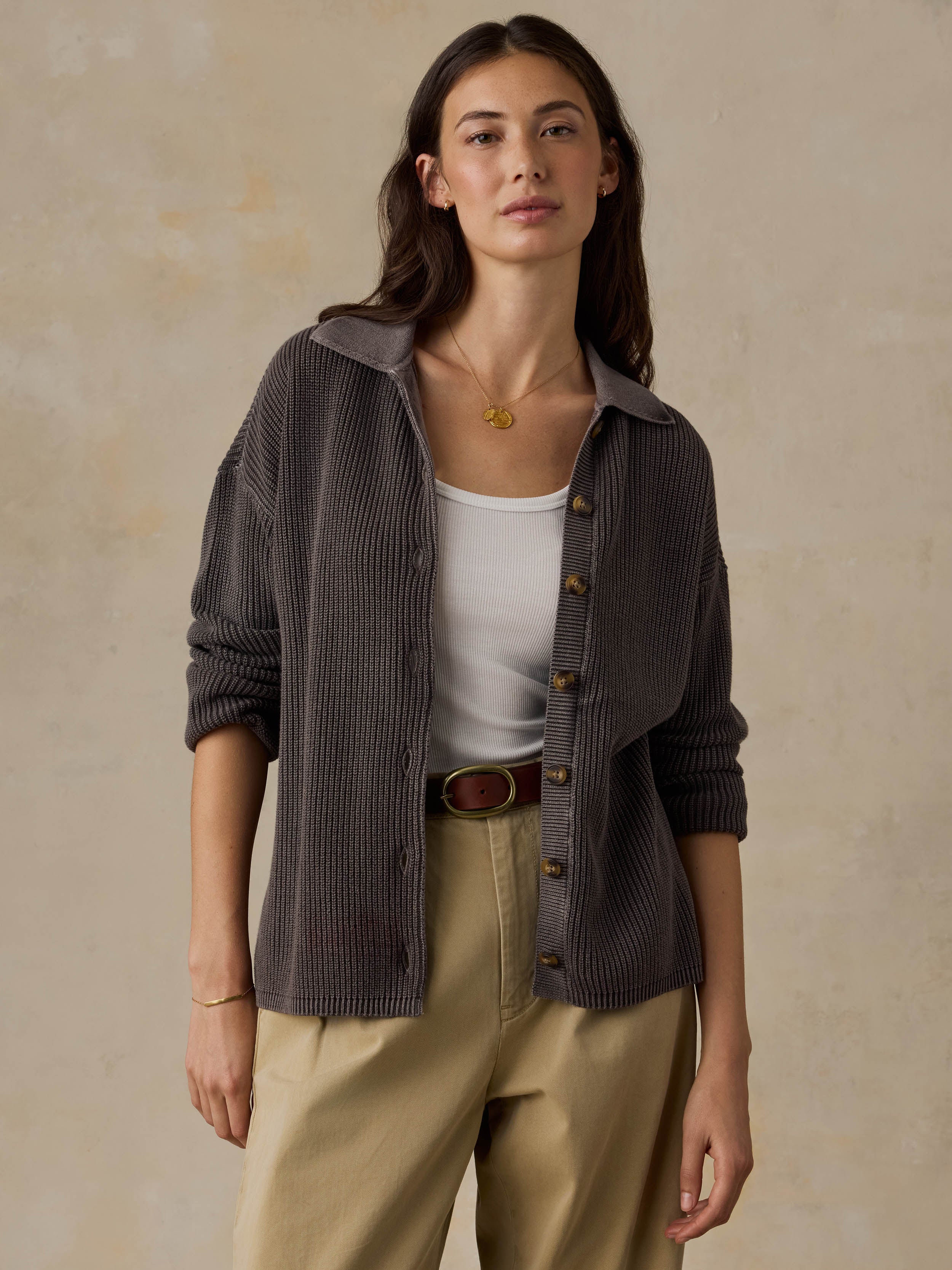Woman wearing a brown sweater and beige pants against a beige background