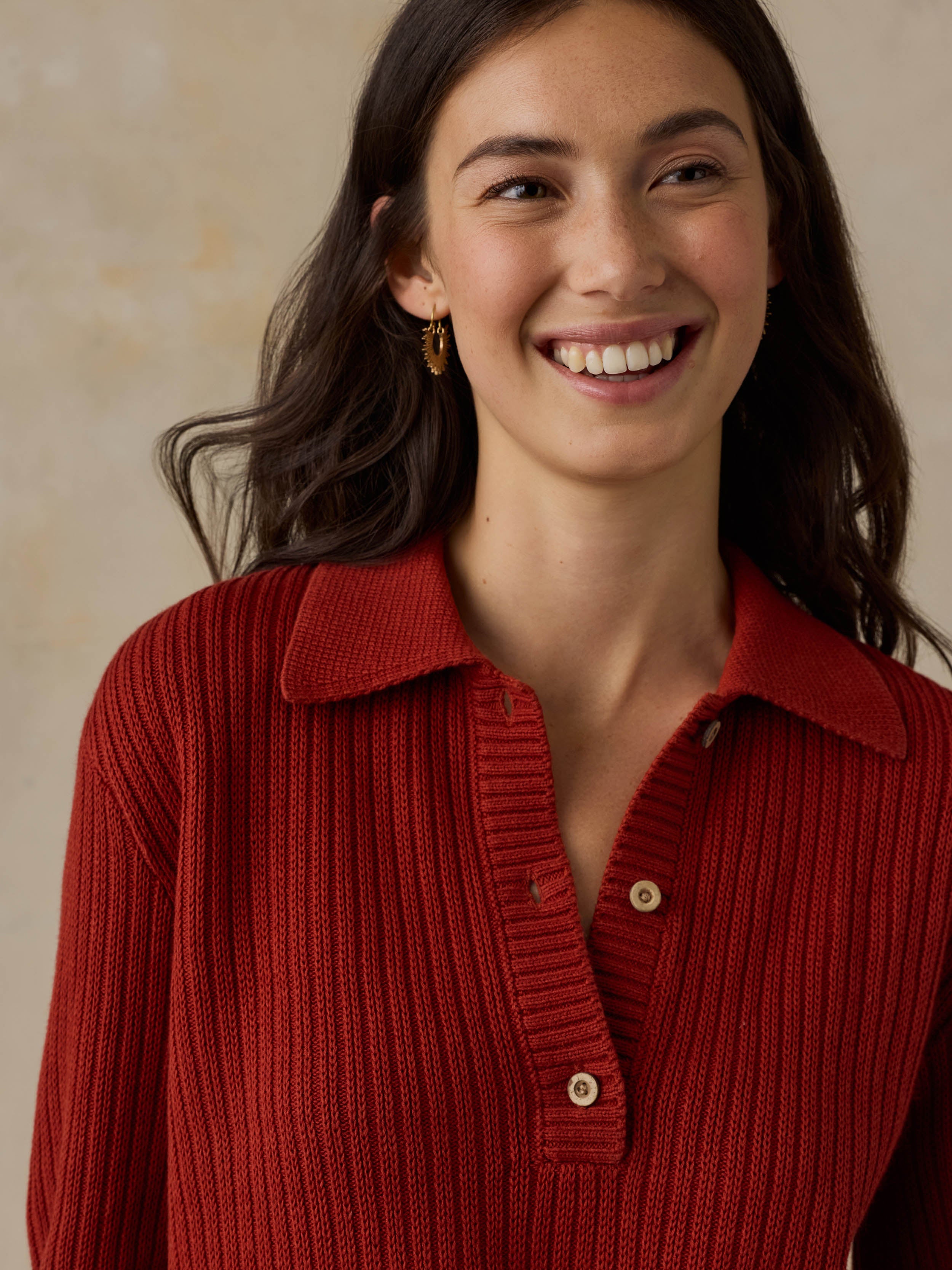 Woman wearing a red ribbed knit polo shirt against a beige background