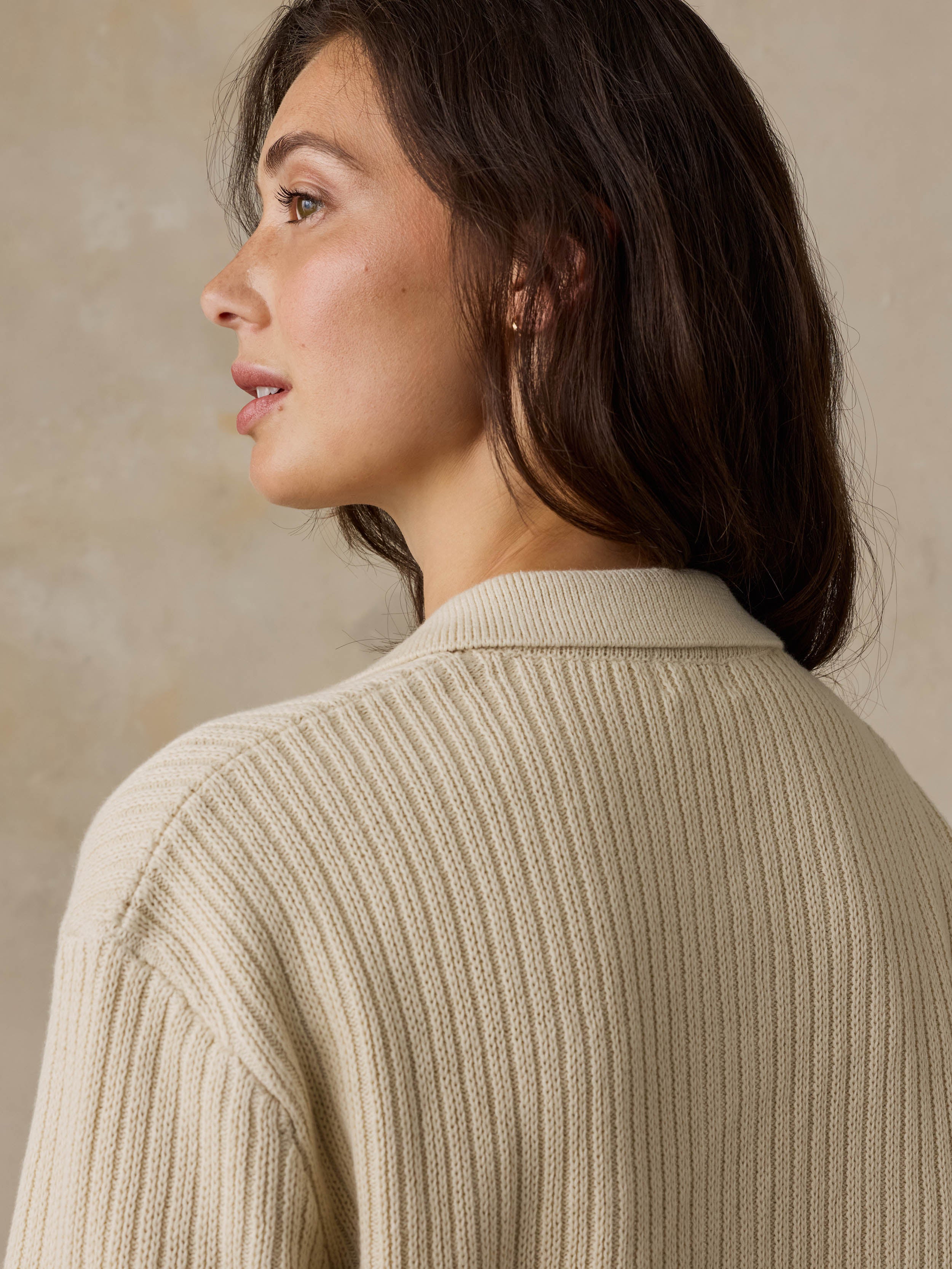 Woman wearing a beige polo against a beige background