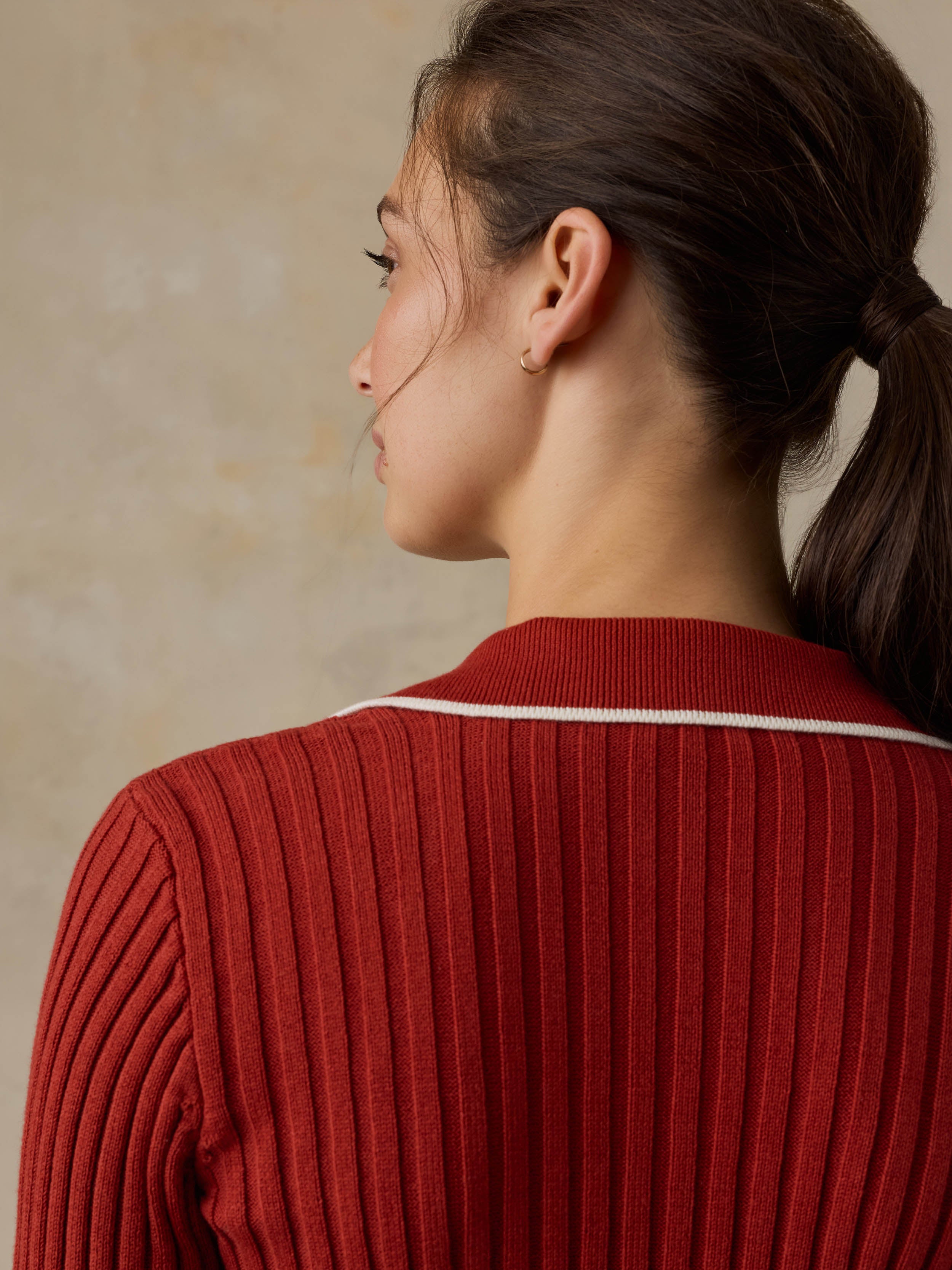 Woman wearing a red cardigan against a beige background