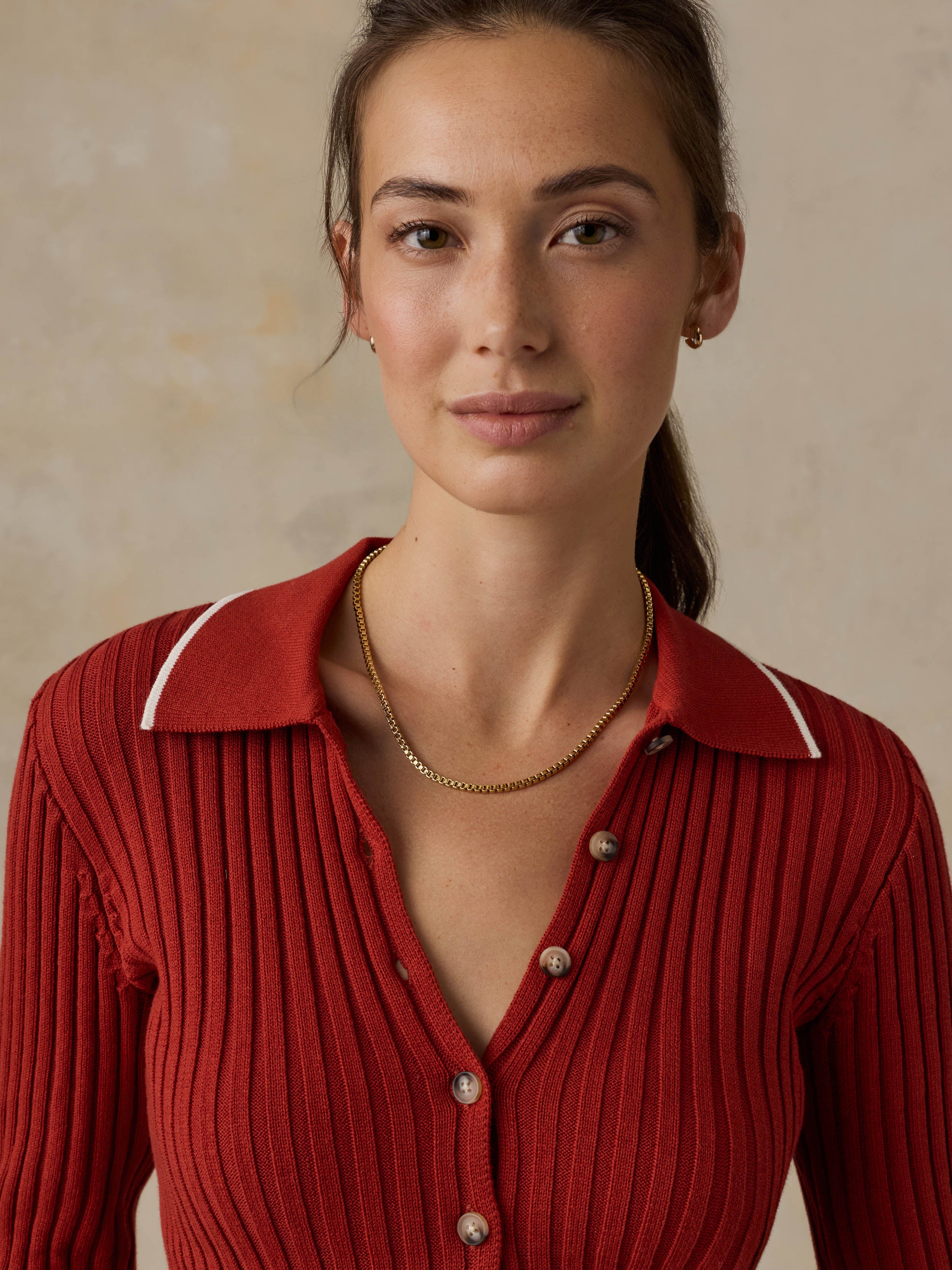 Woman wearing a red cardigan against a beige background