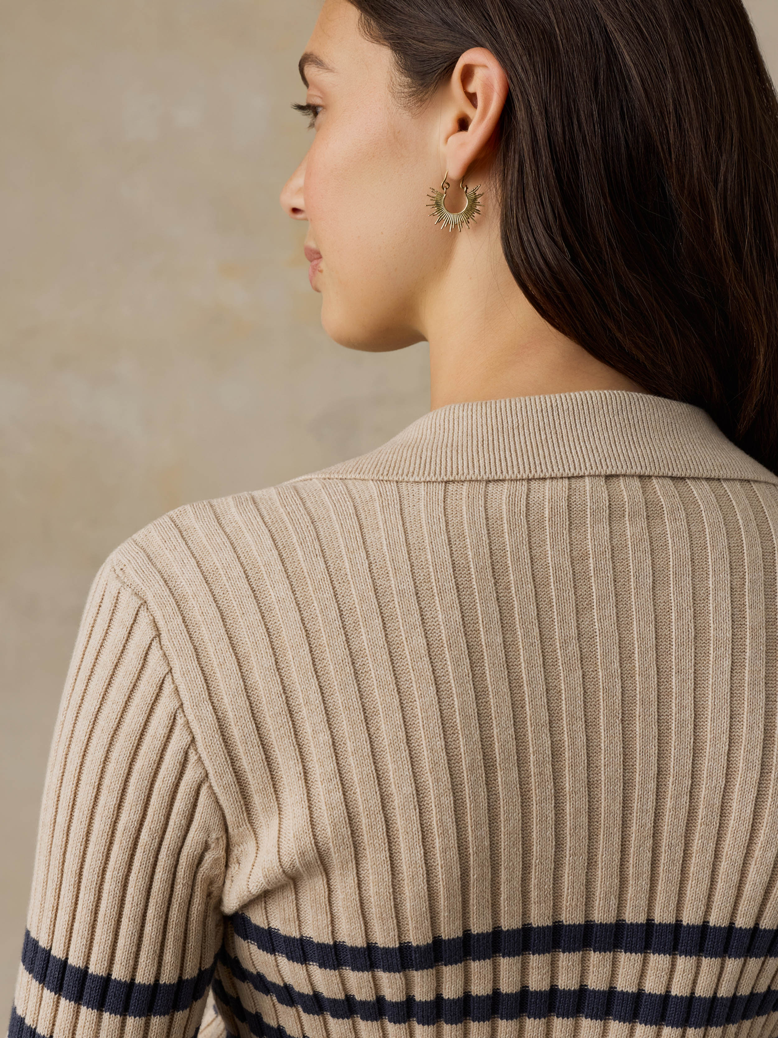 Woman wearing a beige and navy striped cardigan against a beige background