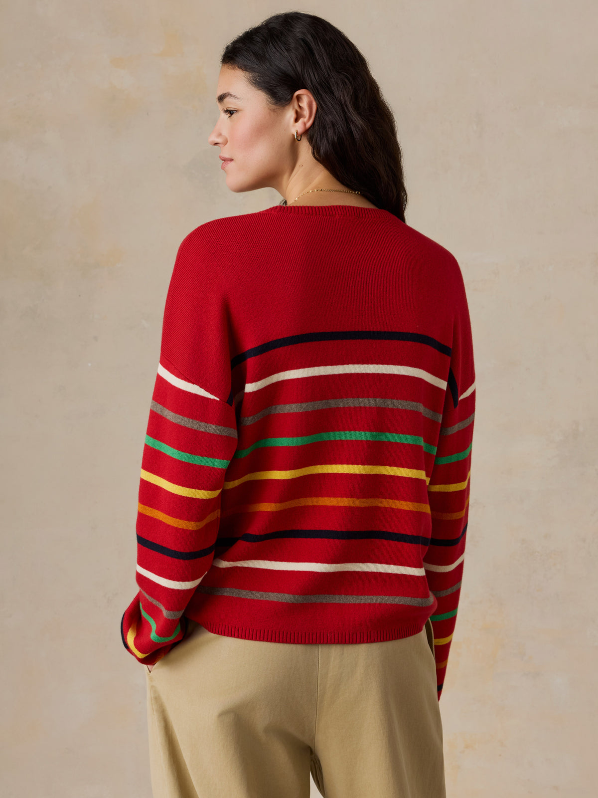A woman viewed from behind wearing a red striped sweater and chino pants, image 3 of 5