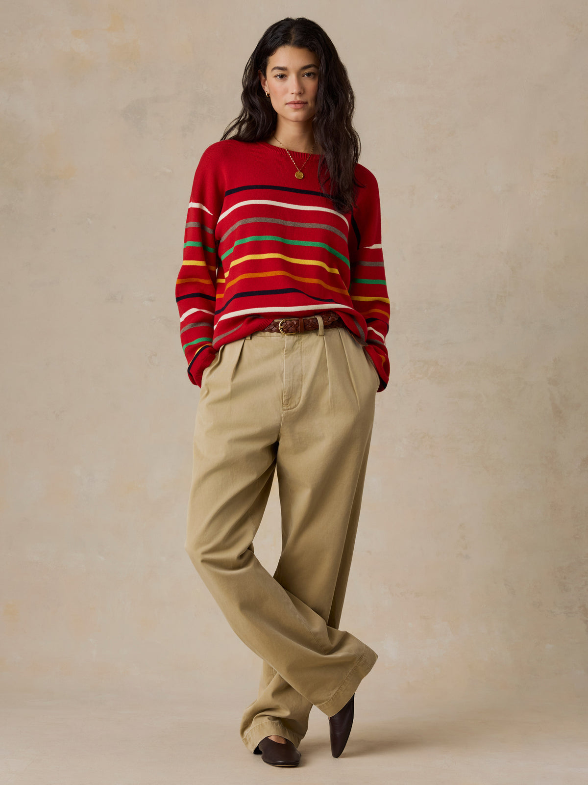 A woman wearing a red striped sweater and chino pants, image 5 of 5