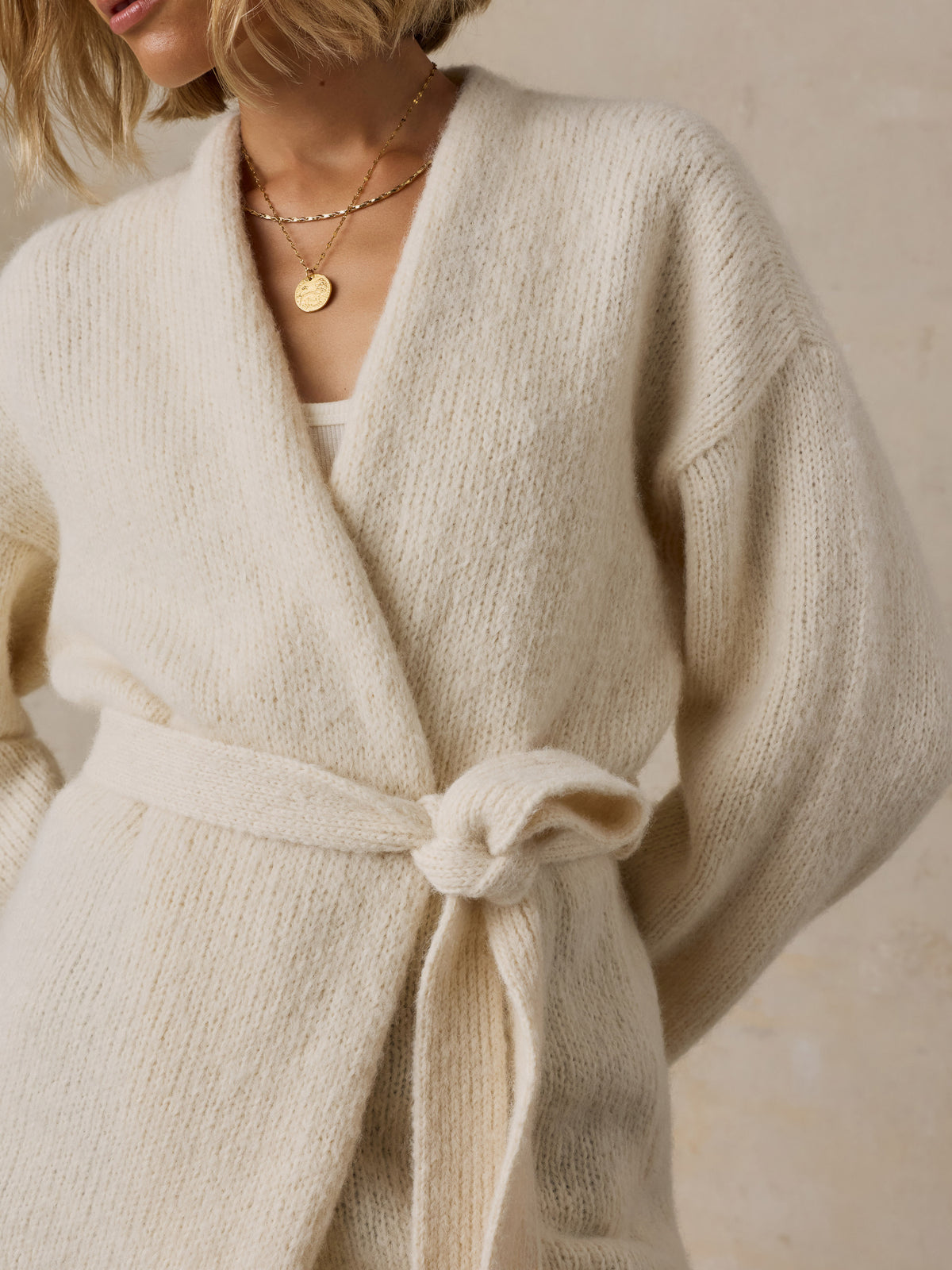 Close up of a woman wearing a cream wrap cardigan, image 5 of 8