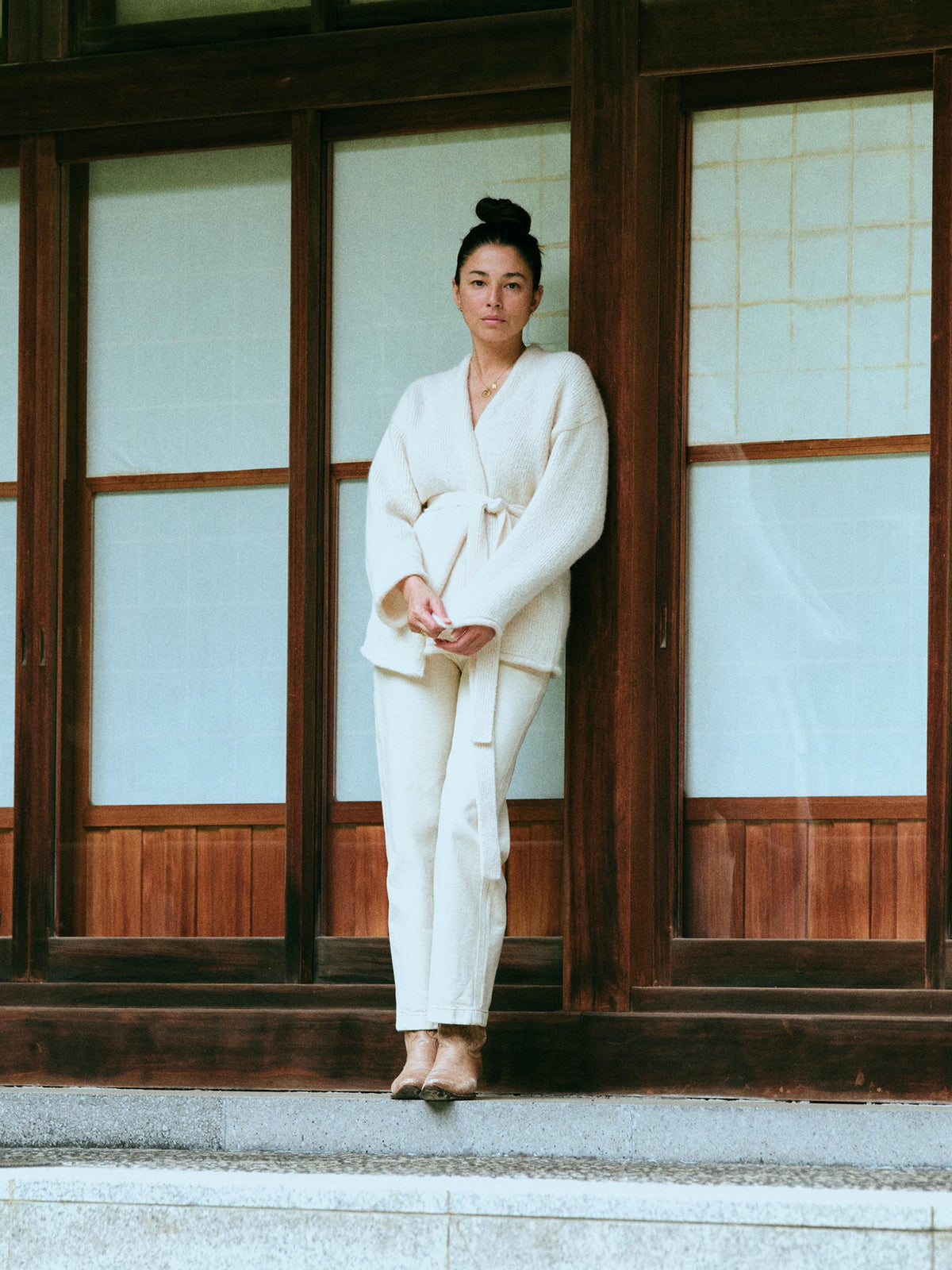 A woman wearing a cream-colored long-sleeve wrap cardigan and white pants., image 8 of 8