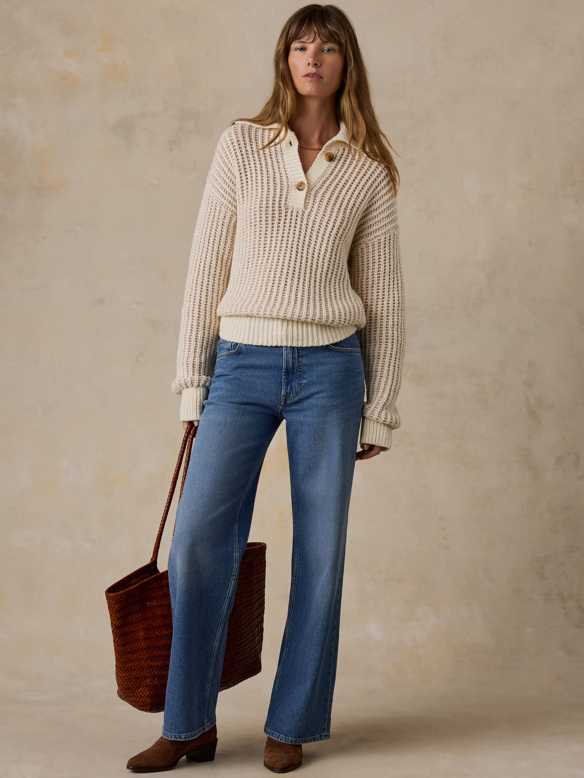 A woman wearing a cream-colored waffle-knit polo sweater and blue jeans, image 5 of 5