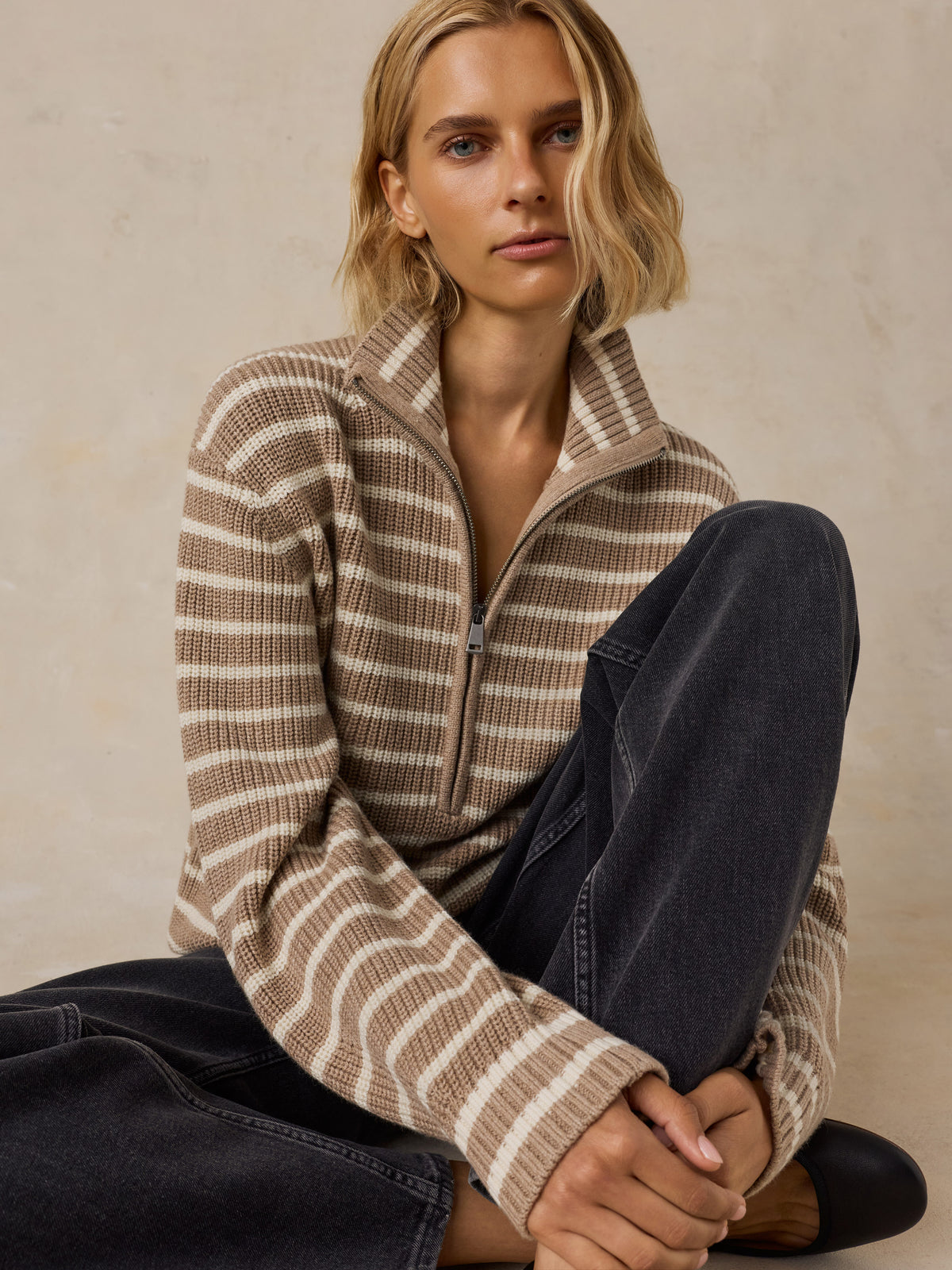 A woman wearing a beige and brown striped quarter-zip pullover sweater with dark wash jeans, image 5 of 5