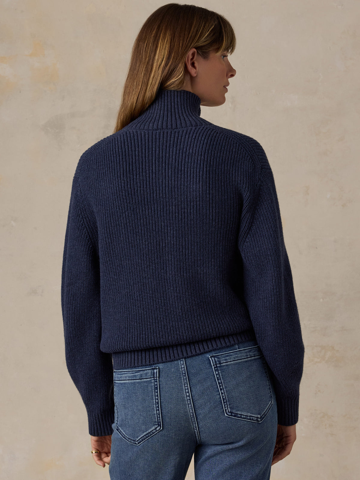 Woman wearing a navy blue quarter zip sweater and blue jeans, image 3 of 6
