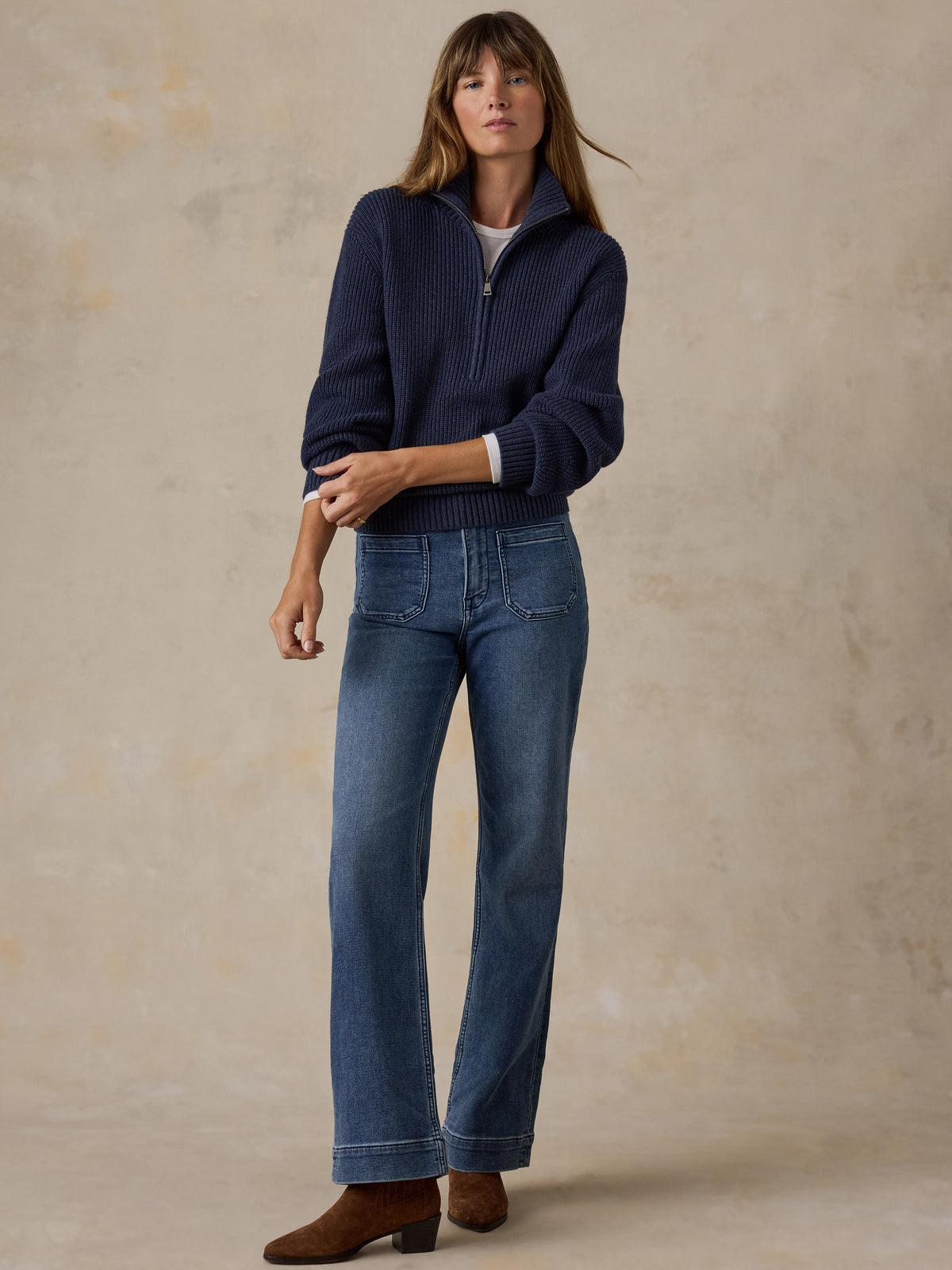 Woman wearing a navy blue quarter zip sweater and blue jeans, image 4 of 6
