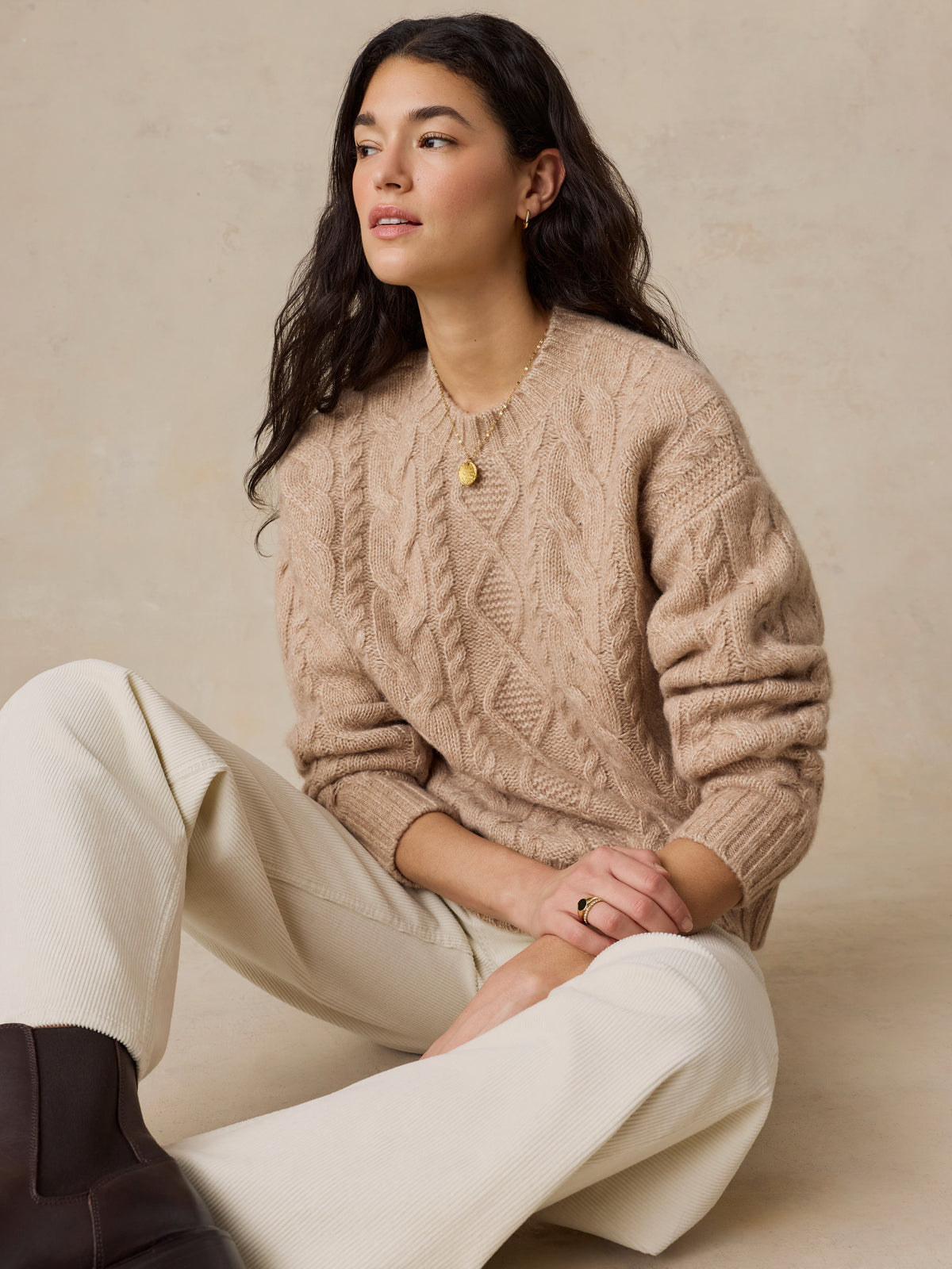 A woman wearing a beige sweater and white pants, image 4 of 5