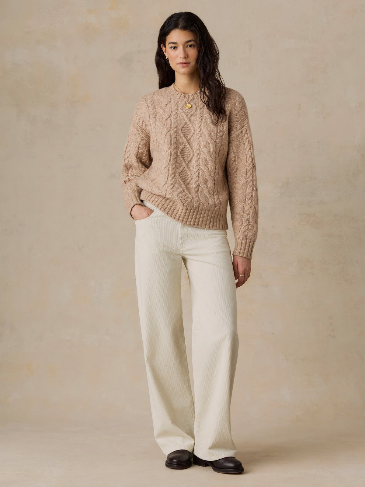 A woman wearing a beige sweater and white pants, image 2 of 5