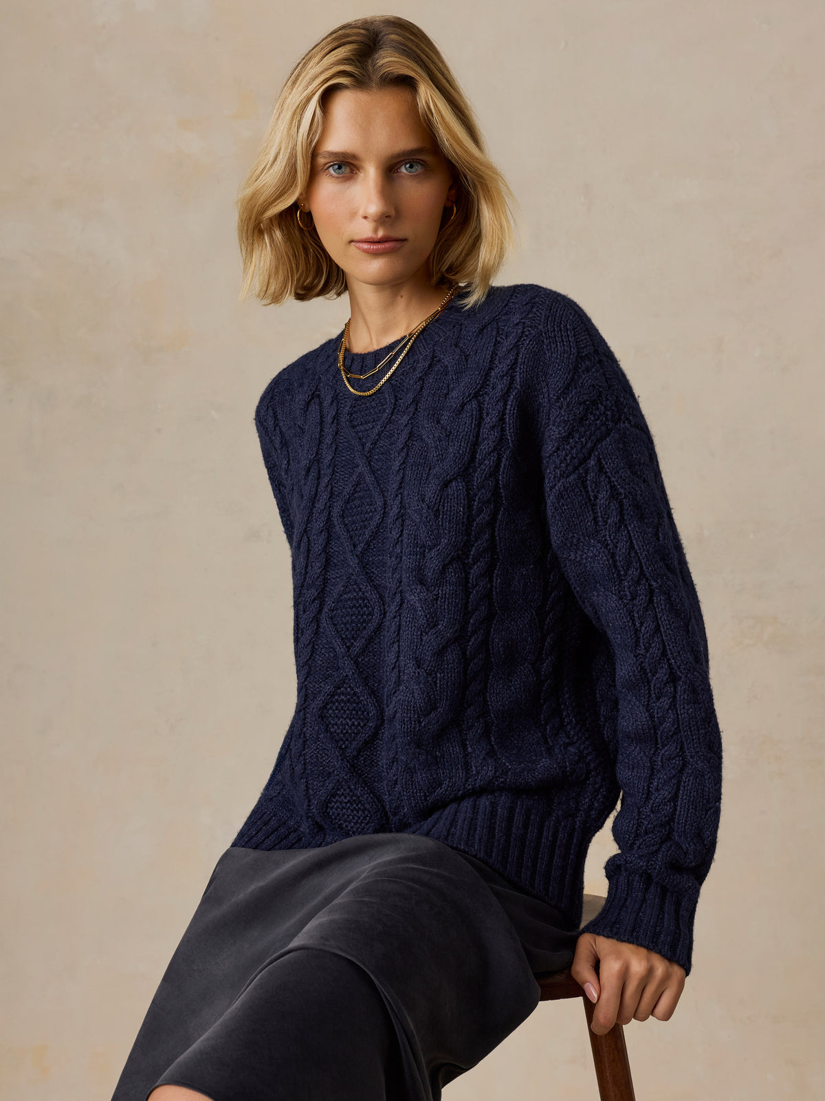 A woman wearing a blue sweater and black skirt, image 3 of 5