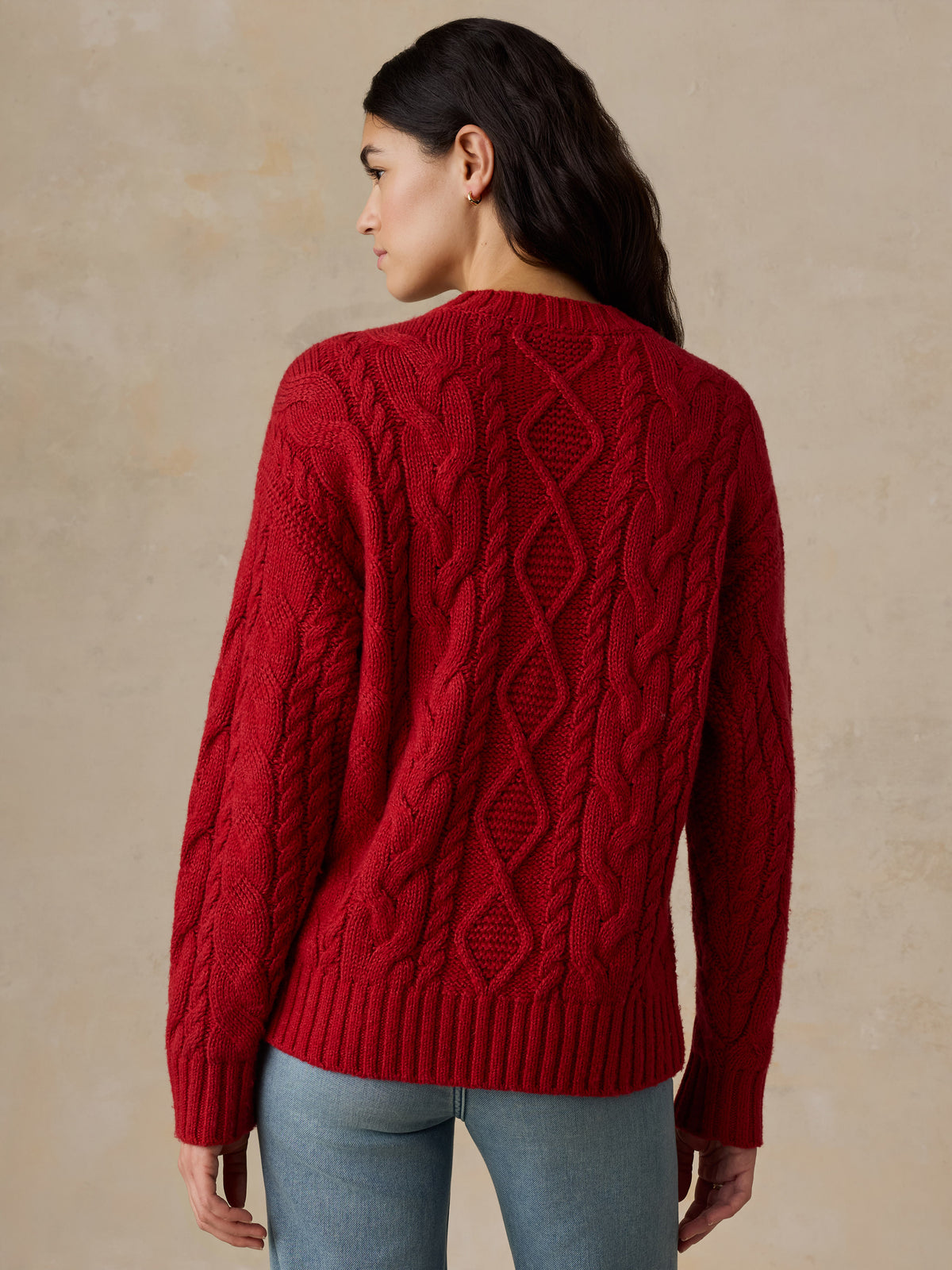 A woman viewed from behind wearing a red sweater and jeans, image 5 of 5