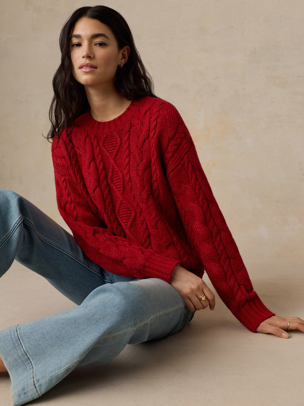 A woman wearing a red sweater and jeans, image 4 of 5