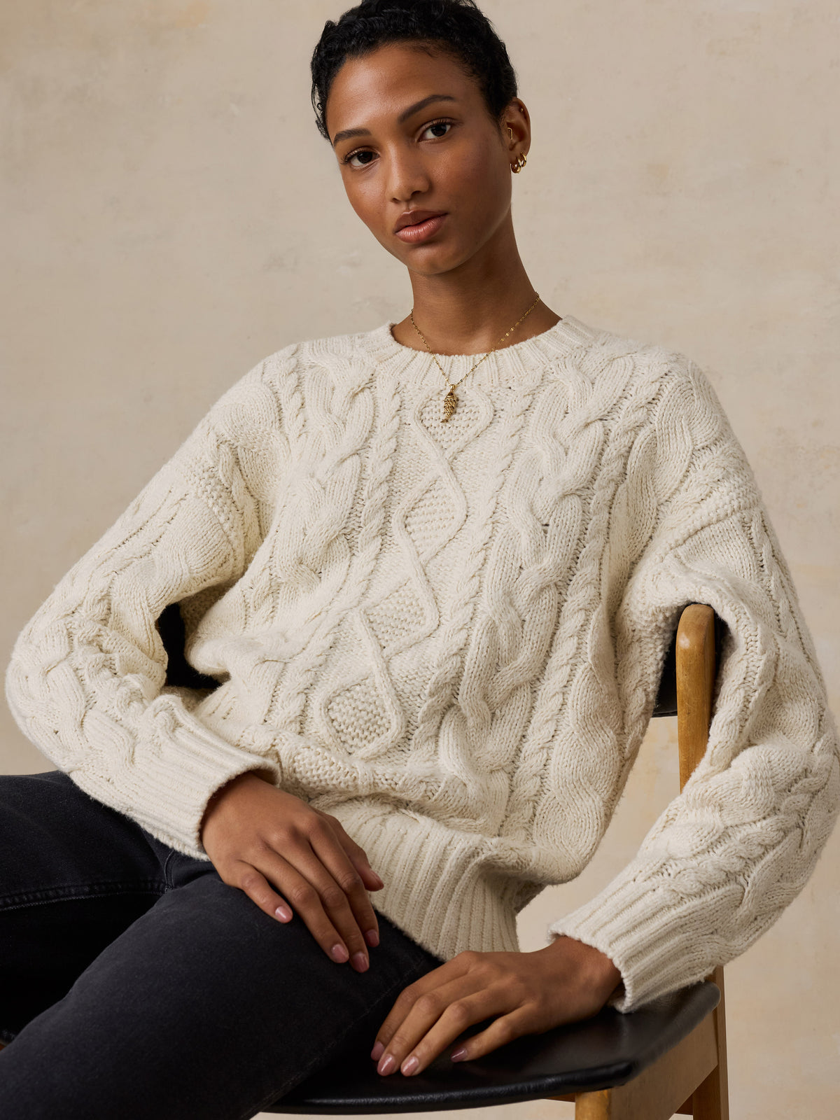 A woman wearing a white sweater and black jeans, image 2 of 5