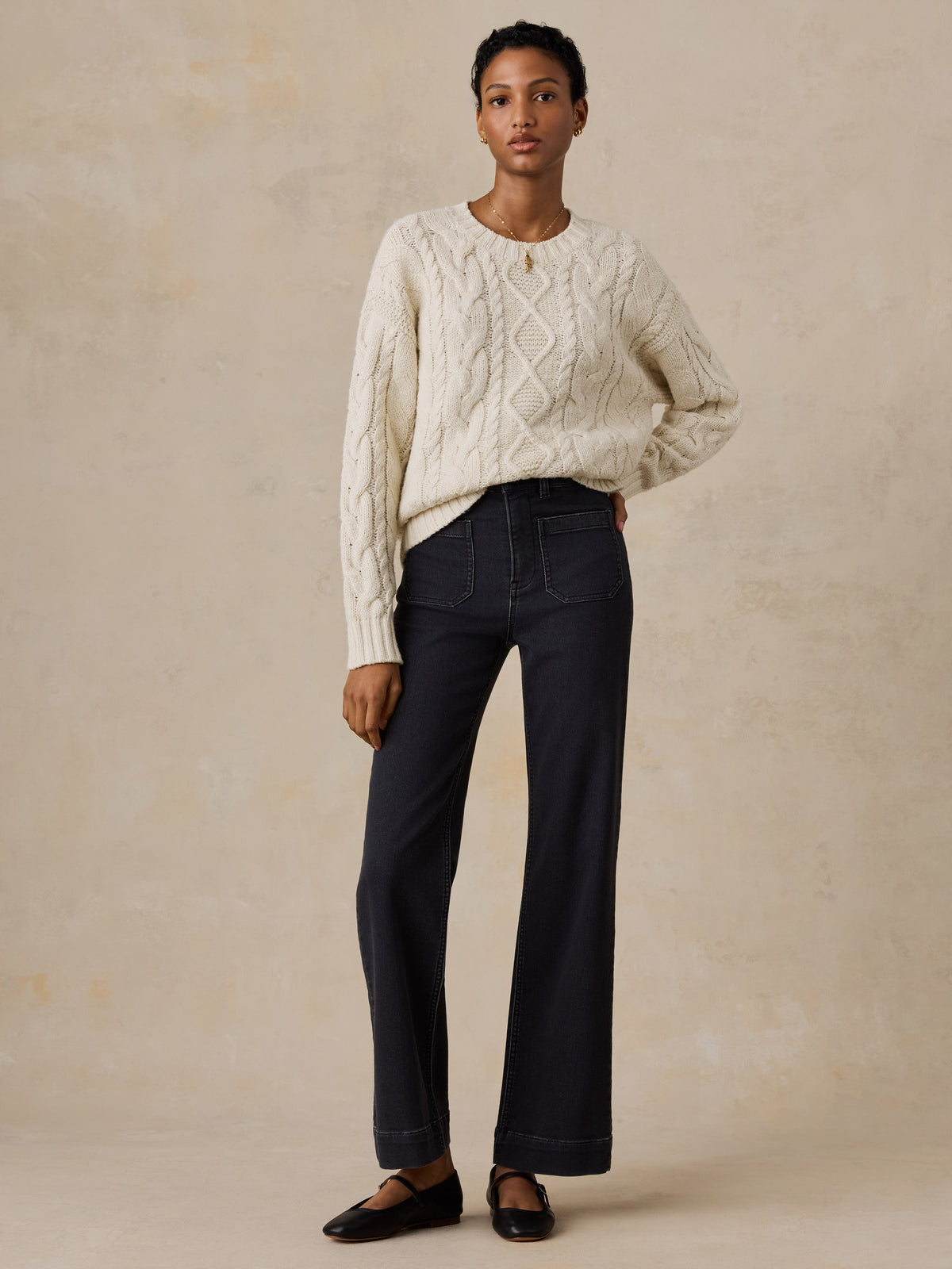 A woman wearing a white sweater and black jeans, image 5 of 5