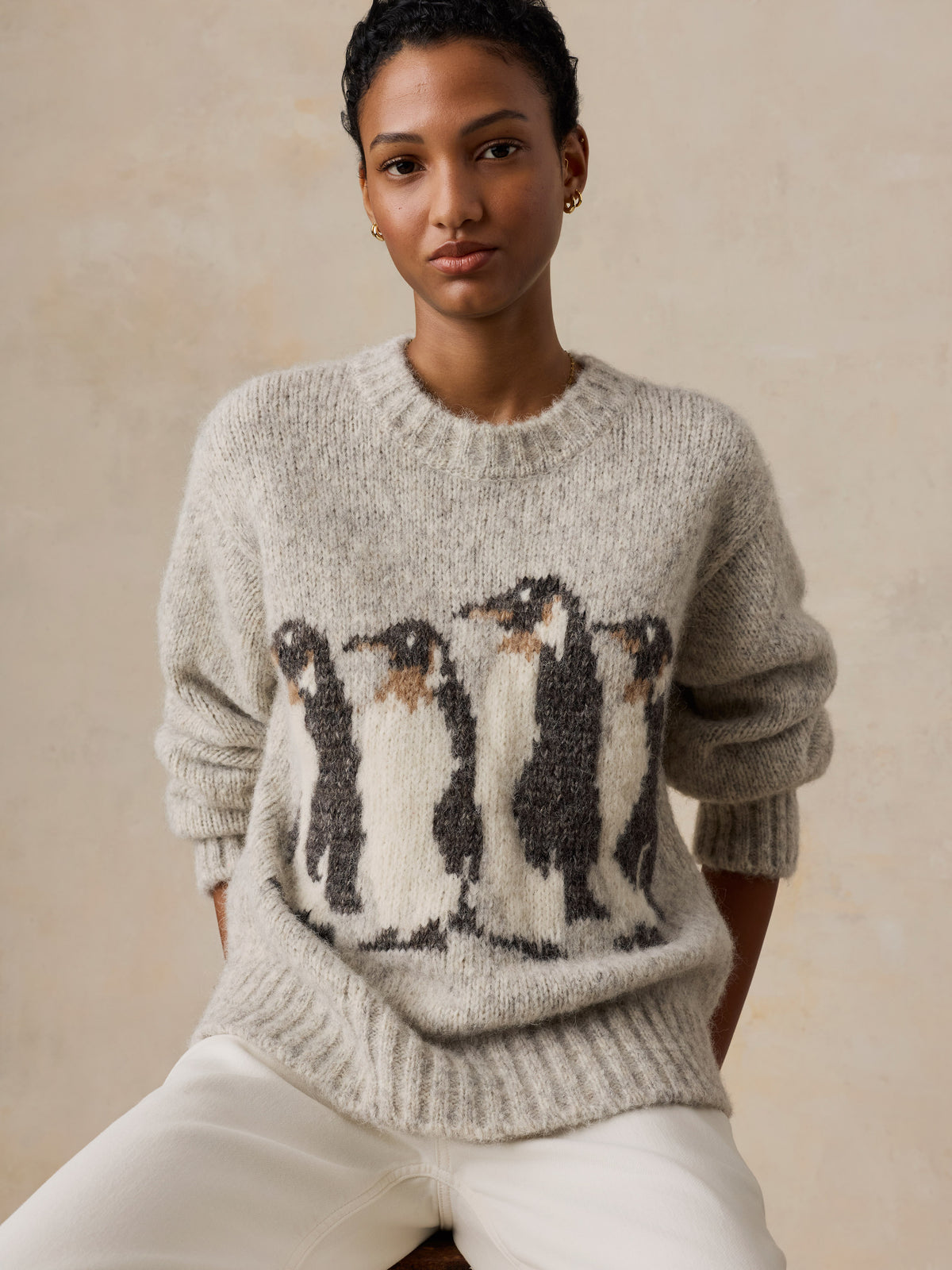 A woman wearing a grey Penguin sweater, image 4 of 5