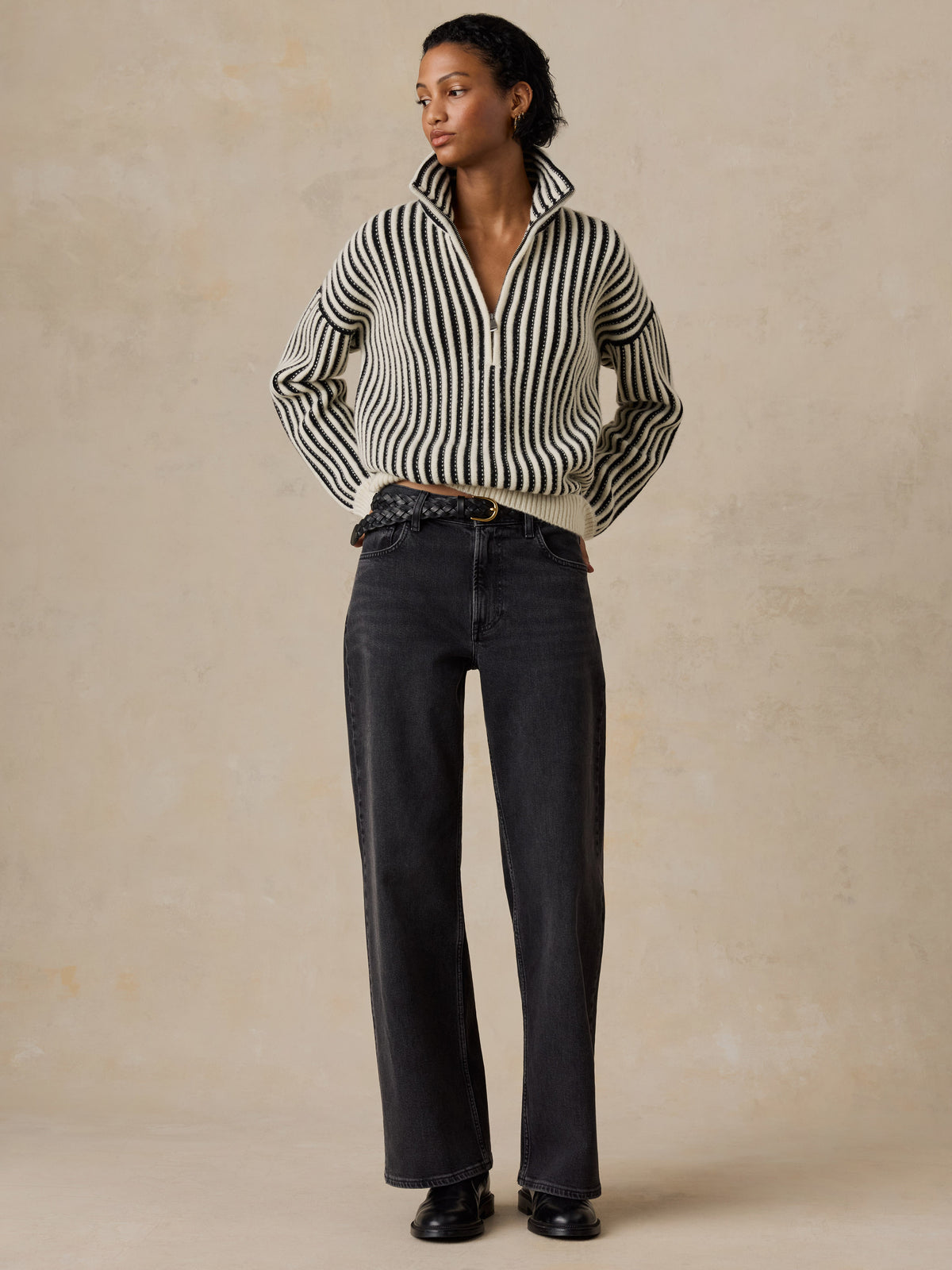 A woman wearing a black and white striped sweater and jeans, image 5 of 5