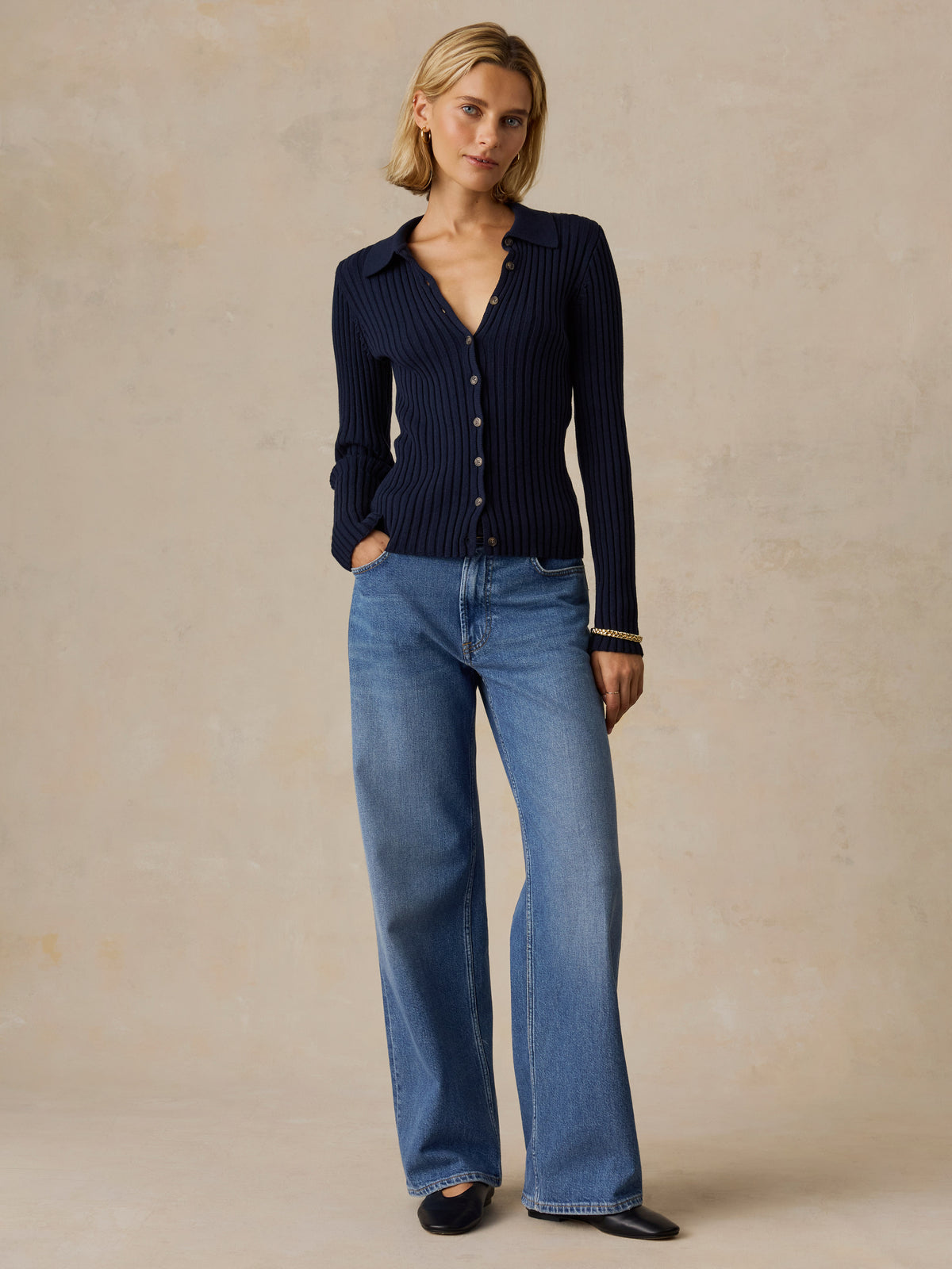 A woman wearing a blue cardigan and jeans, image 5 of 5
