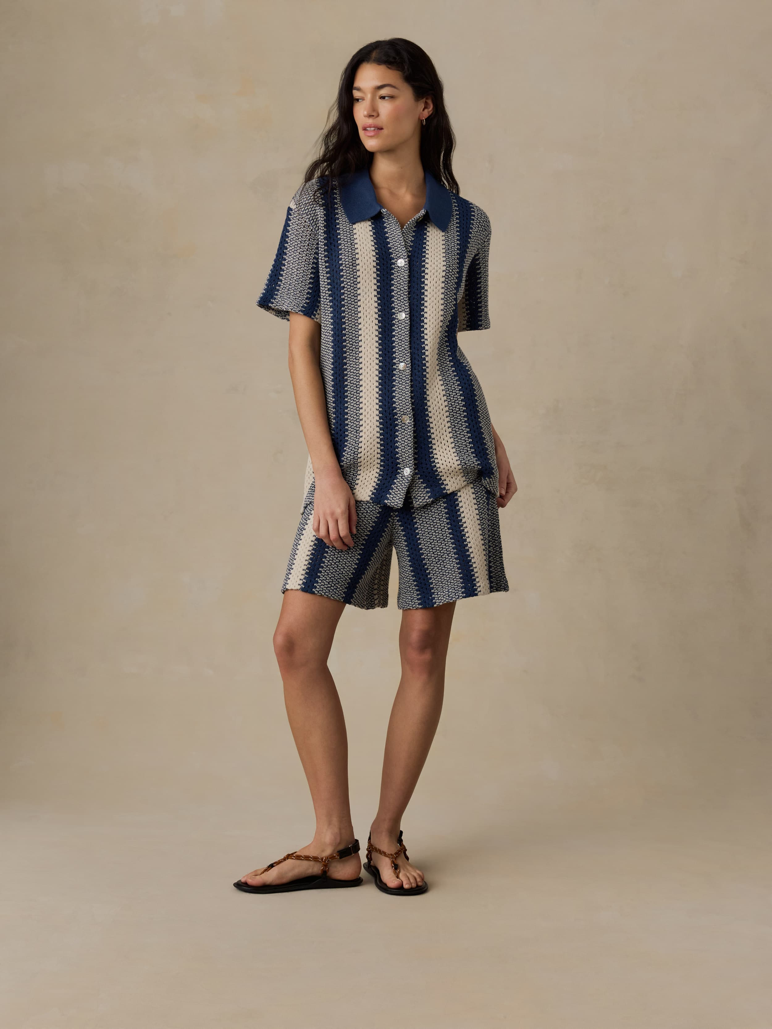 Woman wearing a blue and white striped shirt and matching shorts on a beige background