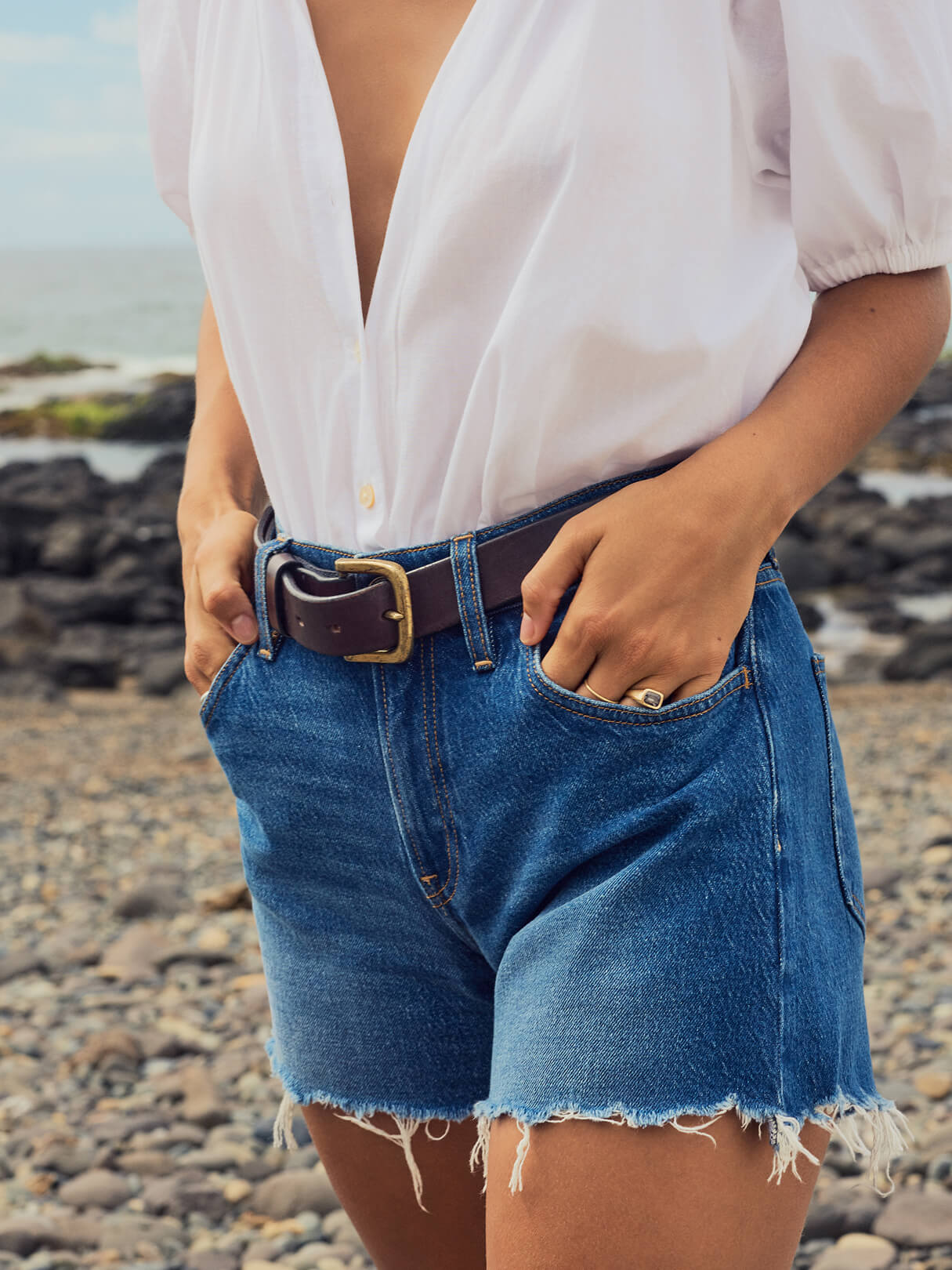 Close up of woman wearing cut off denim shorts with a white blouse