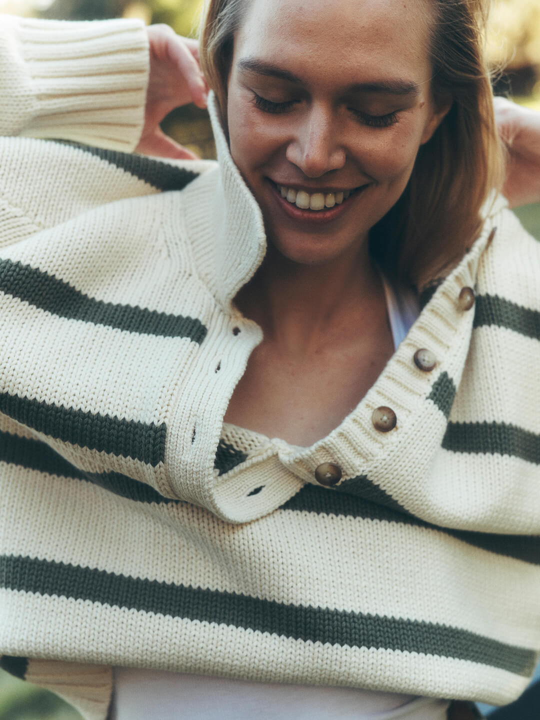 Women's Transitional Sweaters: A close up of a female model putting on a loose knit spring sweater
